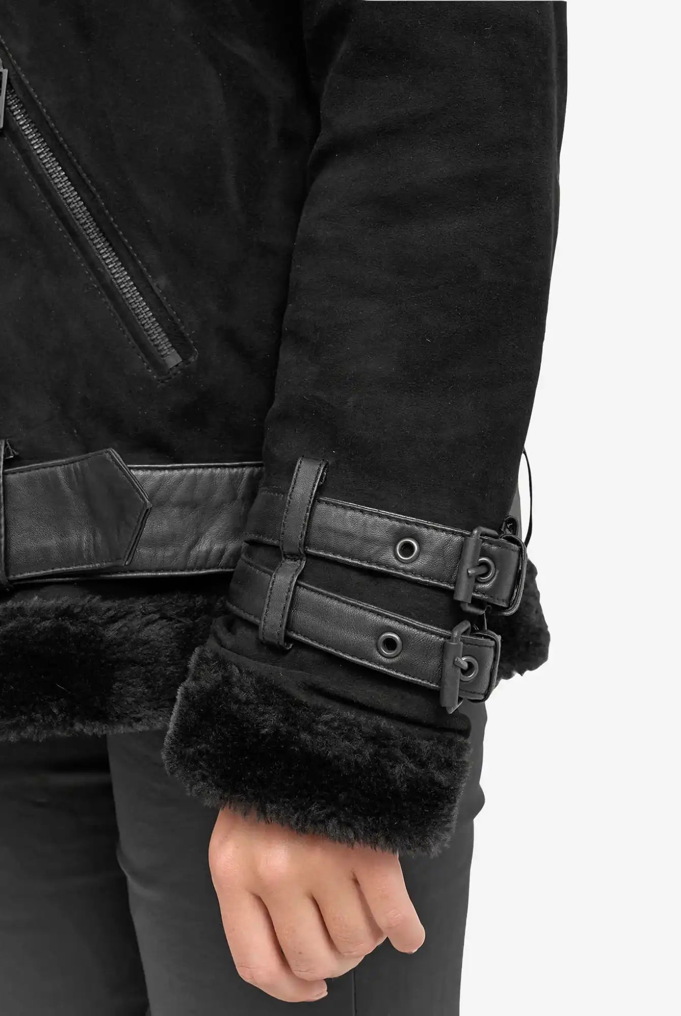 Nahaufnahme des Arms einer Person, die die trueprodigy Aloy Wilderlederjacke mit Gürtel trägt. Sie ist mit schwarzem Kunstfell gefüttert, hat Lederbesätze, zwei Schnallenriemen am Handgelenk und eine Tasche mit Reißverschluss. Nur ein Teil des Oberkörpers und eine Hand sind sichtbar.