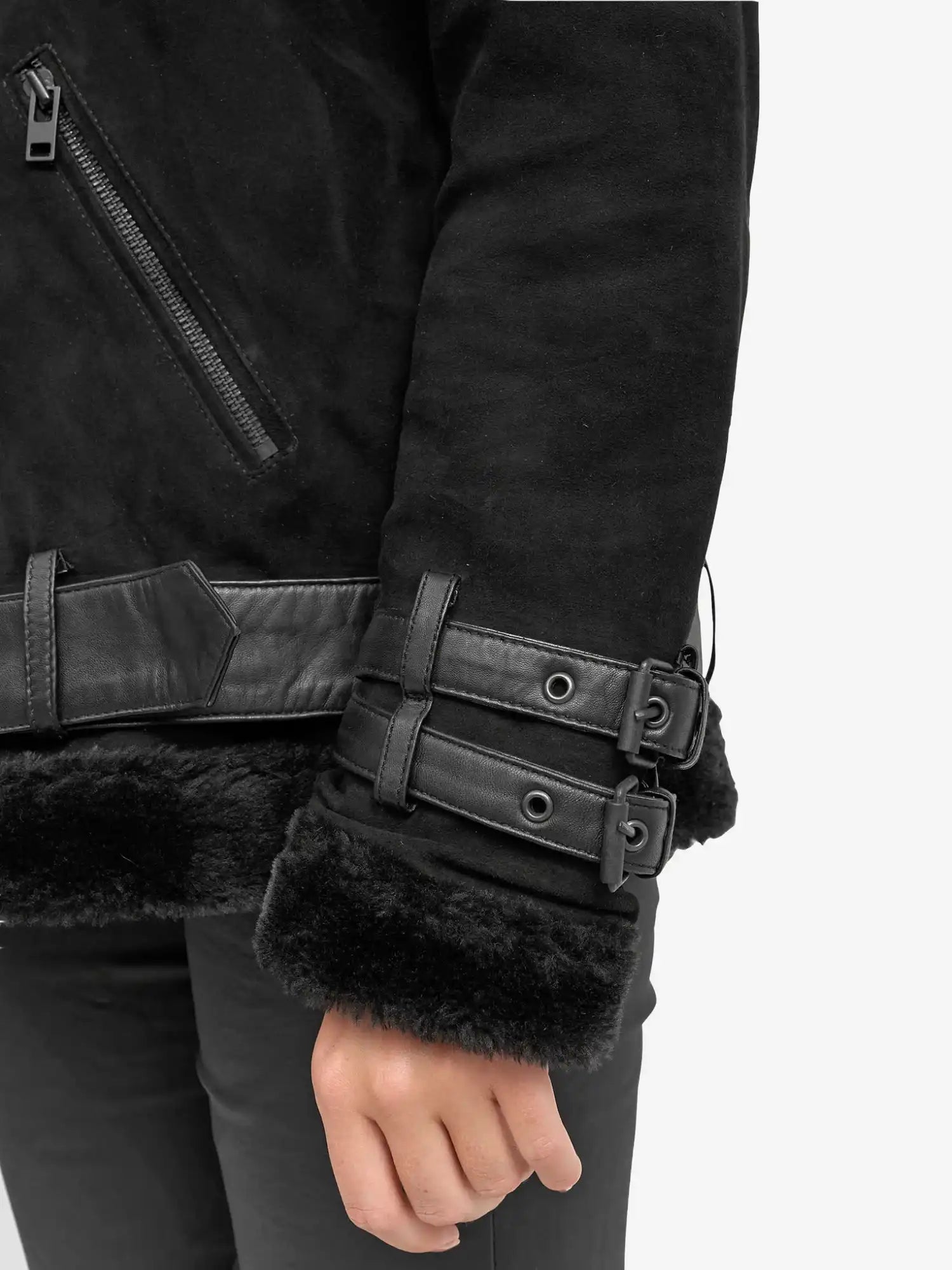 Nahaufnahme des Arms einer Person, die die trueprodigy Aloy Wilderlederjacke mit Gürtel trägt. Sie ist mit schwarzem Kunstfell gefüttert, hat Lederbesätze, zwei Schnallenriemen am Handgelenk und eine Tasche mit Reißverschluss. Nur ein Teil des Oberkörpers und eine Hand sind sichtbar.