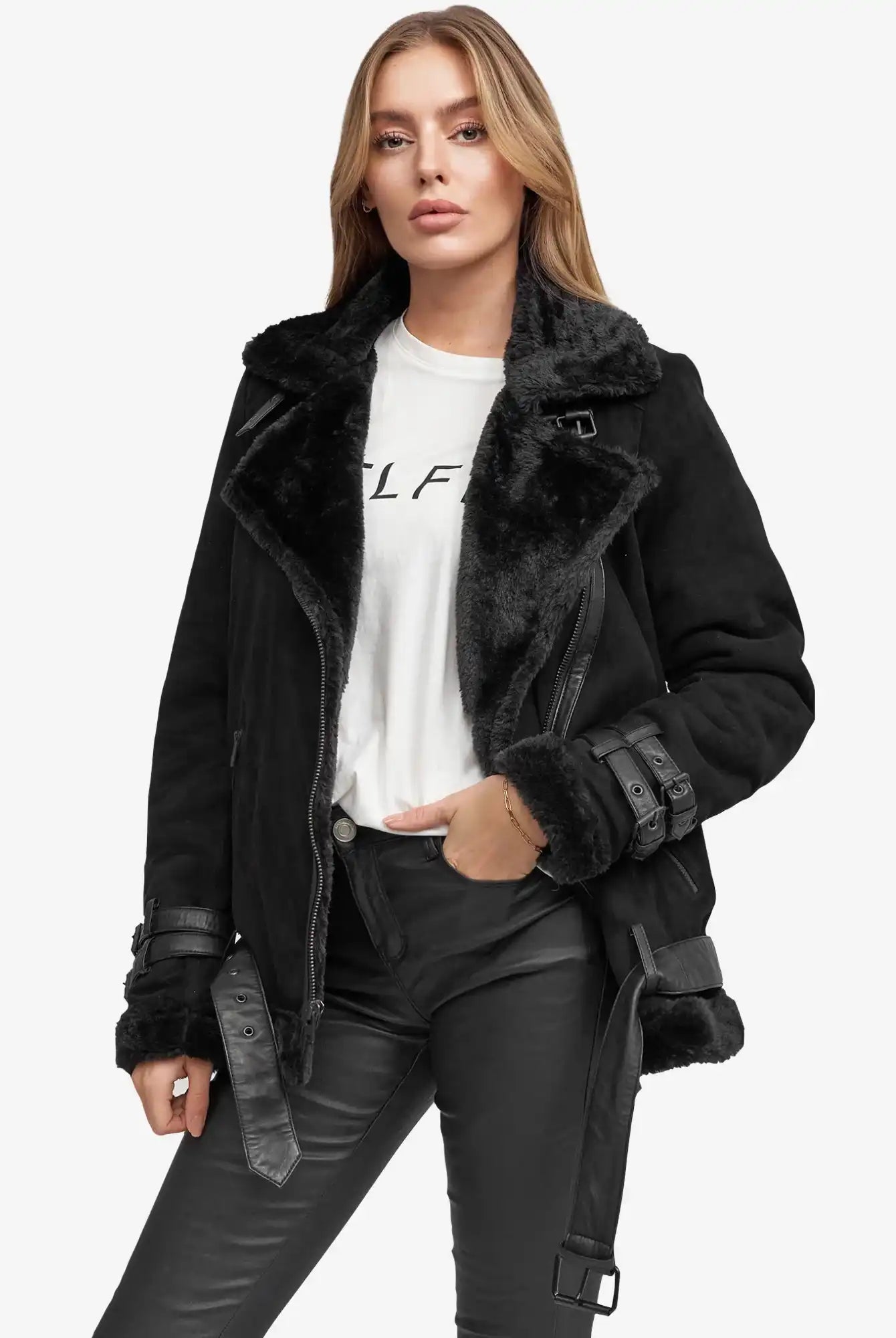 Eine Person mit langen, hellbraunen Haaren trägt eine Aloy Wilderlederjacke mit Gürtel über einem weißen T-Shirt und einer schwarzen Lederhose und steht vor einem schlichten weißen Hintergrund.