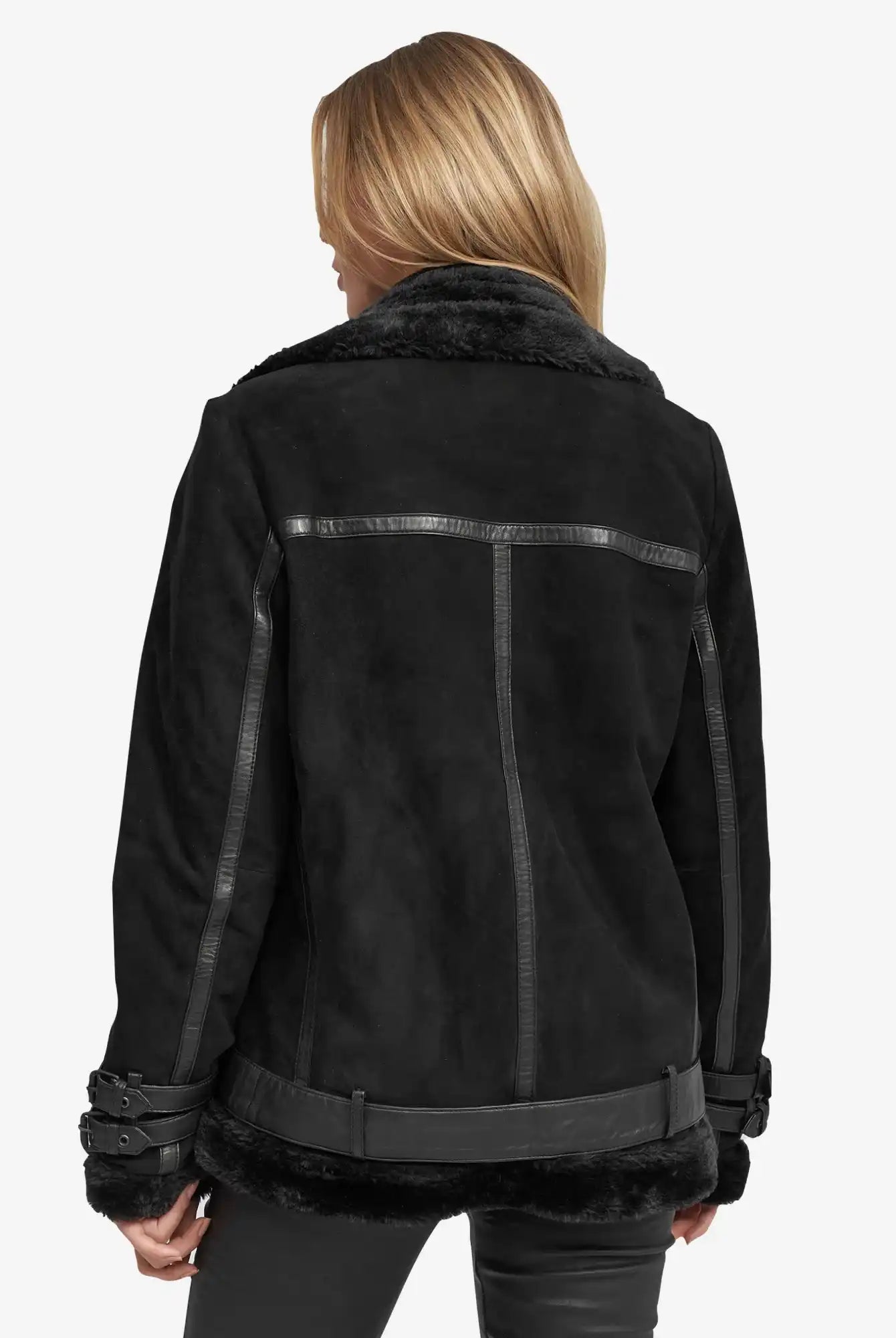 Eine Person mit blondem Haar, von hinten gesehen, trägt eine schwarze Trueprodigy Aloy Wilderlederjacke mit Gürtel mit Lederbesatz und Schnallendetails an den Ärmeln und der Taille, gestylt mit einer schwarzen Hose.