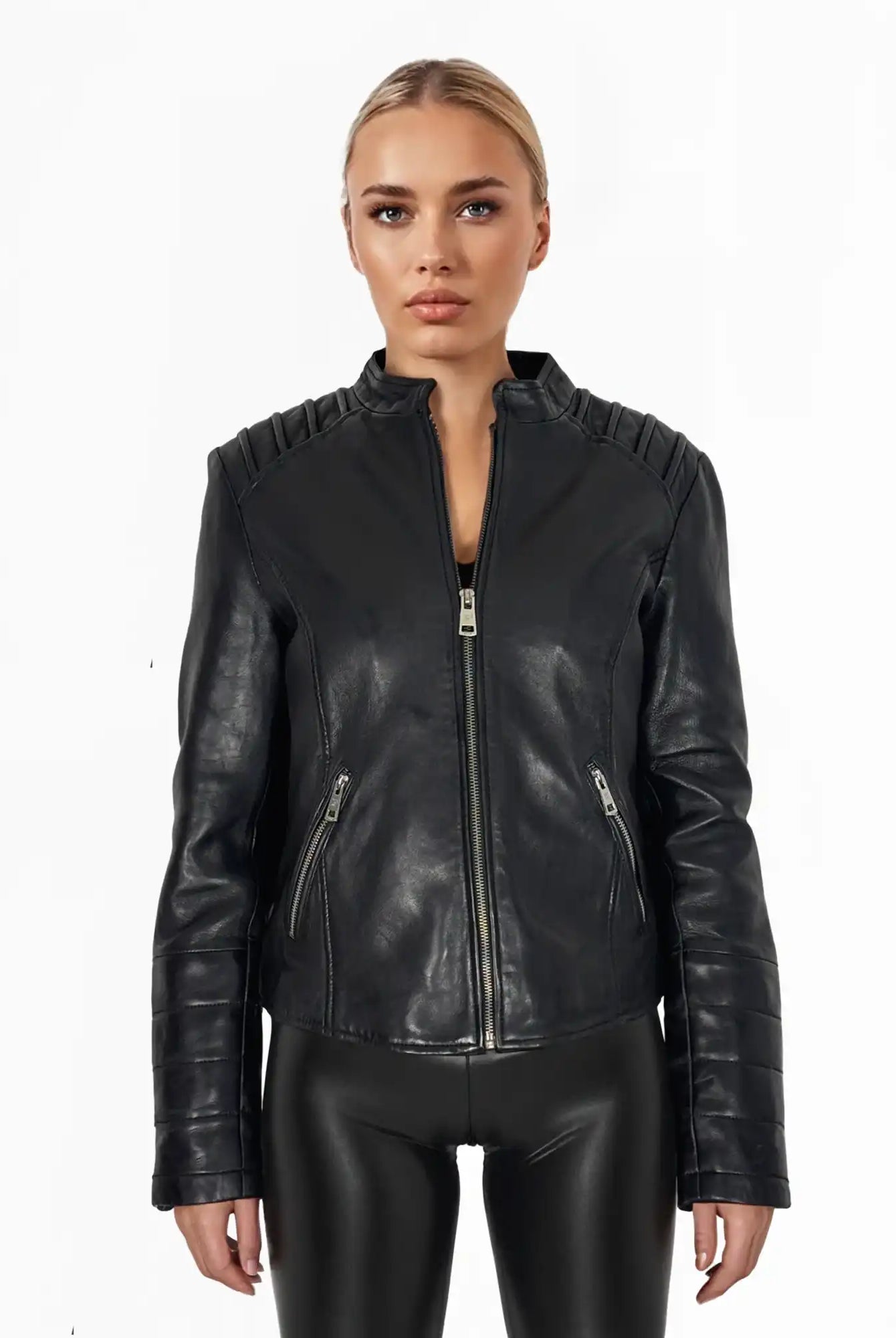 Eine Frau blickt nach vorne und trägt die trueprodigy Raegan taillierte Lederjacke mit Stehkragen, Steppnähten & silbernen Reißverschlüssen, gepaart mit einer schwarzen Hose vor einem weißen Hintergrund.