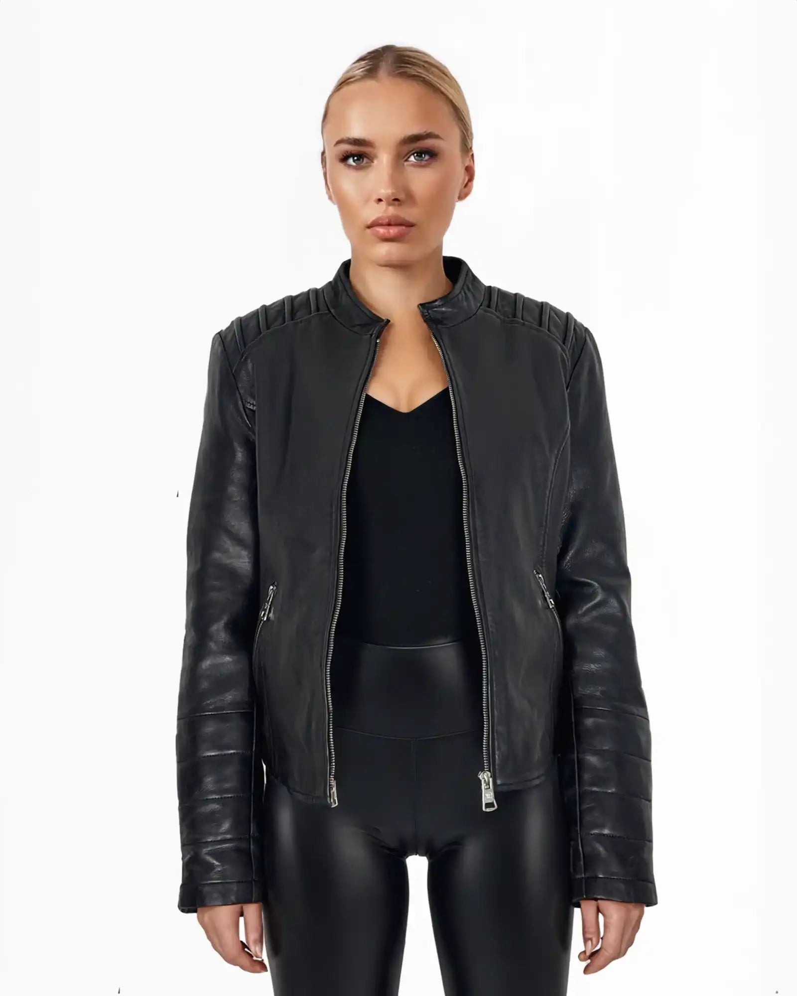 Eine Person steht vor weißem Hintergrund und trägt die Raegan taillierte Lederjacke mit Stehkragen, Steppnähten und silbernen Reißverschlüssen von trueprodigy über schwarzem Top und Hose. Ihr Ausdruck ist neutral.