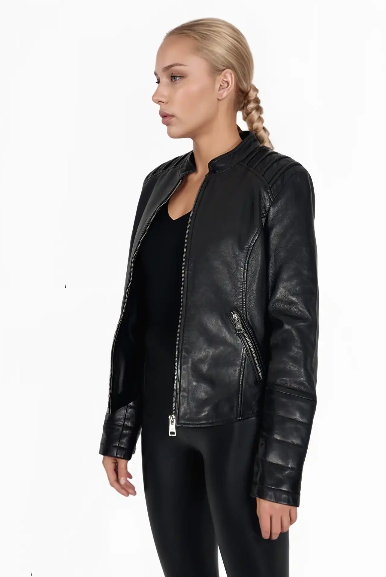 Eine blonde Frau mit einem Zopf trägt die Trueprodigy Raegan taillierte Lederjacke mit Stehkragen, Steppnähten & silbernen Reißverschlüssen und schwarze Hosen, stehend vor einem schlichten weißen Hintergrund, leicht nach links gewandt.