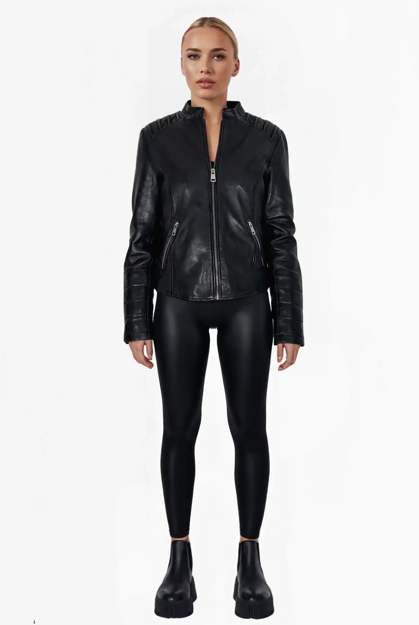 Eine Person trägt die "Raegan" taillierte Lederjacke mit Stehkragen, Steppnähten & silbernen Reißverschlüssen von trueprodigy, dazu glänzende Leggings und schwarze Chunky-Platform-Schuhe vor weißem Hintergrund.