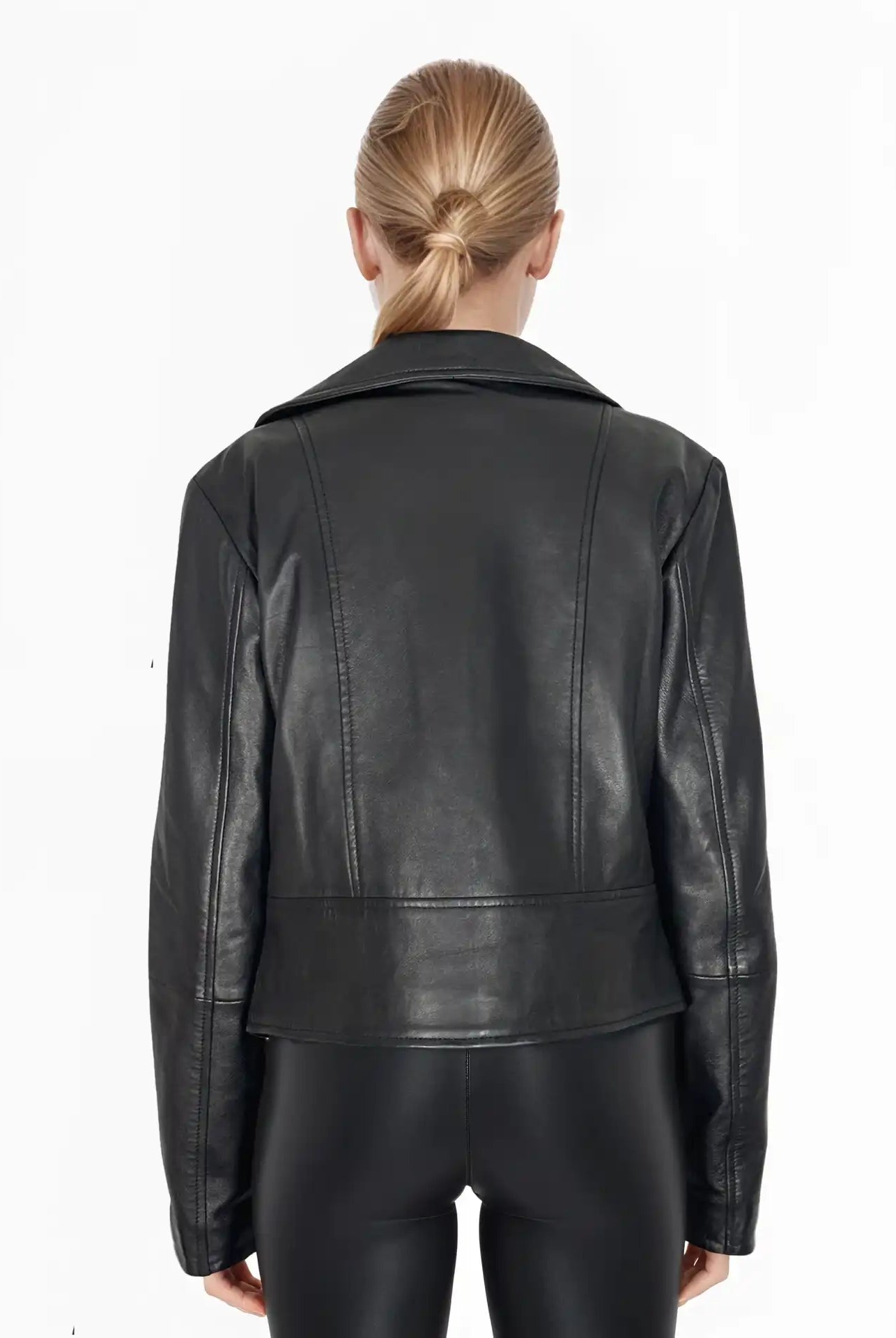 Eine Person mit blondem Haar in einem tiefen Dutt wird von hinten gezeigt, die die trueprodigy Stella taillierte Lederjacke mit schwarzem Reißverschluss & Ärmelzipper und eine schwarze Hose vor einem weißen Hintergrund trägt.