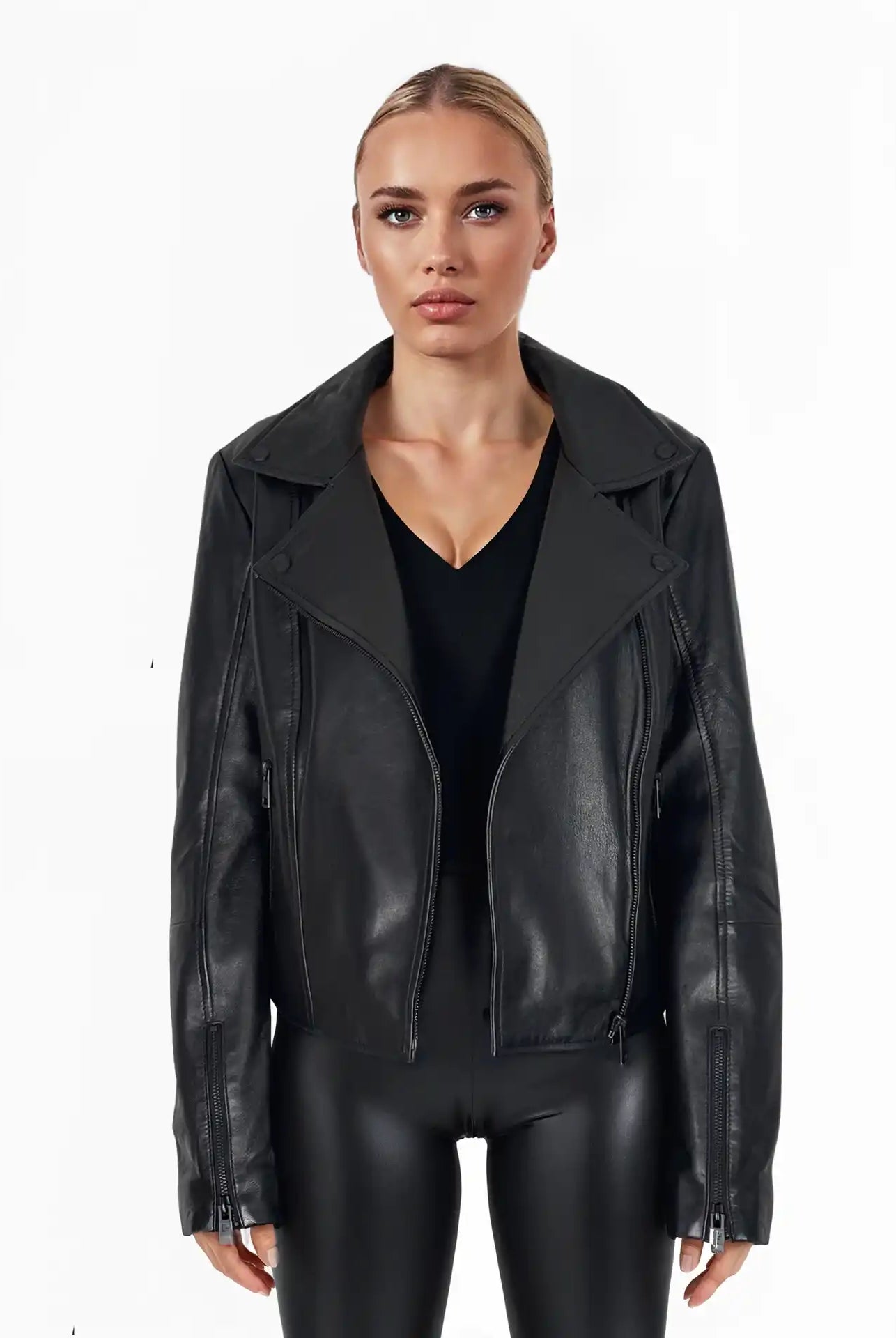 Eine Frau trägt die Stella Taillierte Lederjacke mit schwarzem Reißverschluss & Ärmelzipper von trueprodigy über einem schwarzen Top und glänzenden Leggings, ihr blondes Haar ist zurückgebunden, vor schlicht weißem Hintergrund.