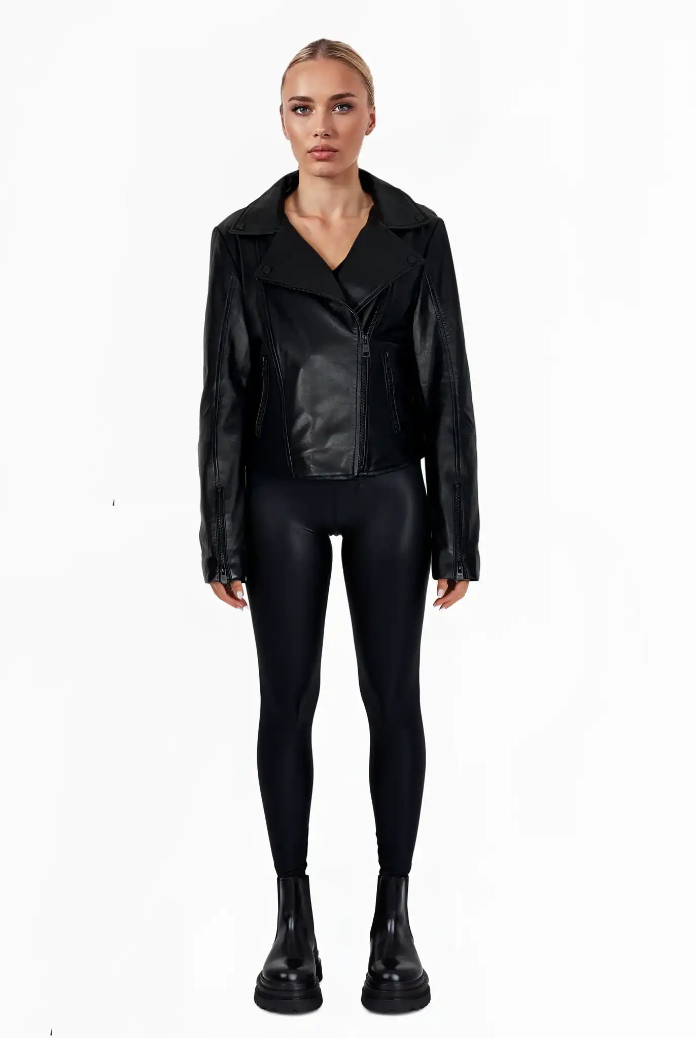 Eine Person steht mit dem Gesicht nach vorne und trägt die trueprodigy Stella taillierte Lederjacke mit schwarzem Reißverschluss & Ärmelzipper, schwarze Leggings und schwarze Ankle Boots. Der Hintergrund ist einfarbig weiß.