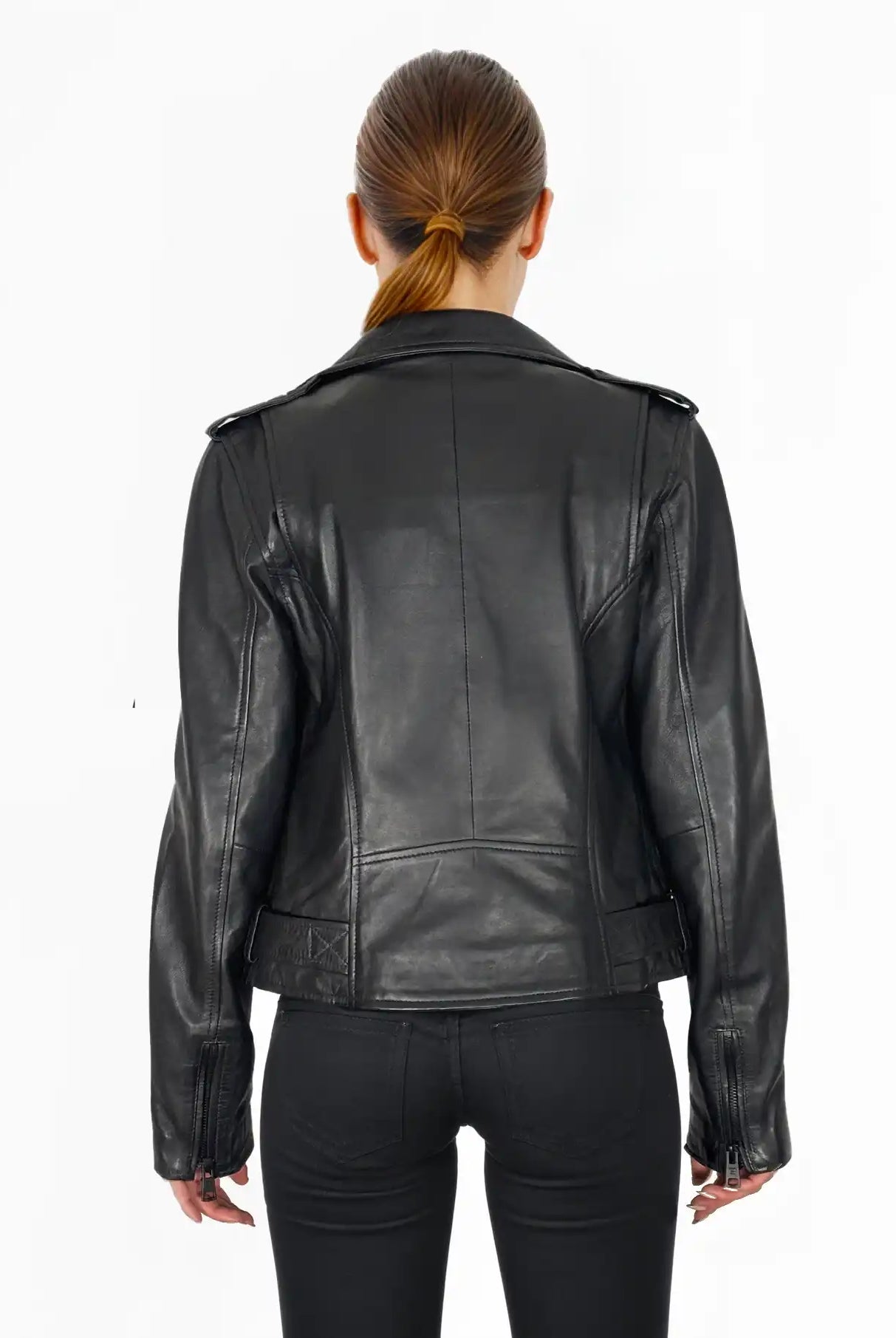 Eine Person mit braunen Haaren in einem niedrigen Pferdeschwanz wird von hinten gezeigt. Sie trägt eine trueprodigy Laura Feminine Bikerjacke mit Gürtel & Schulterriegeln und eine schwarze Hose vor einem schlichten weißen Hintergrund.