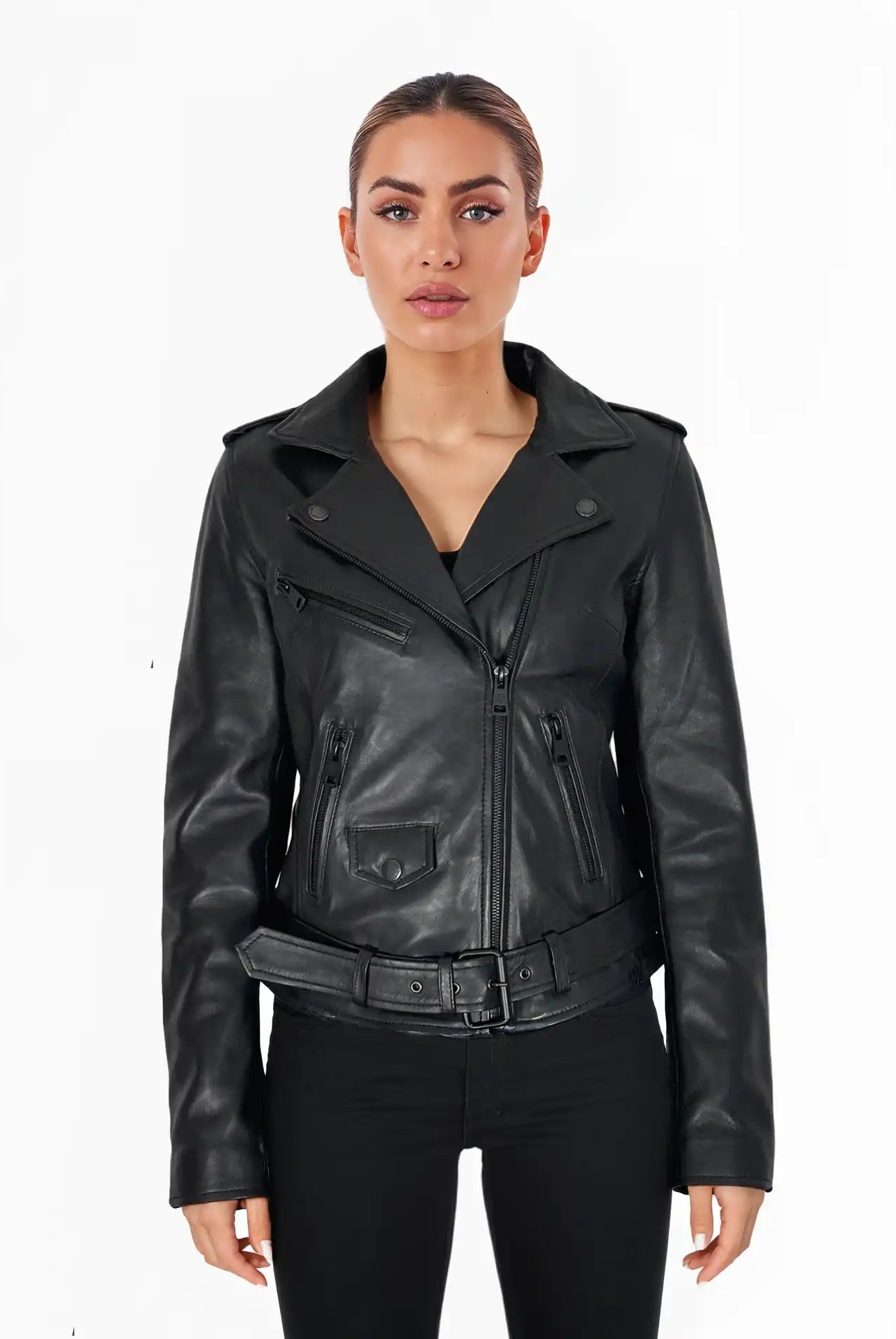 Eine Frau steht mit dem Gesicht nach vorne vor einem weißen Hintergrund und trägt die trueprodigy Laura Feminine Bikerjacke mit Gürtel & Schulterriegeln und eine schwarze Hose. Ihr Haar ist hochgesteckt, und sie hat einen neutralen Gesichtsausdruck.