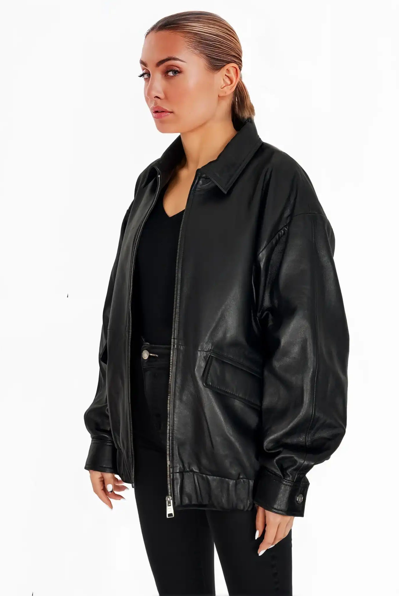 Eine hellhäutige Person mit zurückgekämmten Haaren trägt die trueprodigy Nova Oversize-Lederjacke mit Gummizugsaum & Lederdetails über einem schwarzen Oberteil und einer Hose vor einem schlichten weißen Hintergrund.