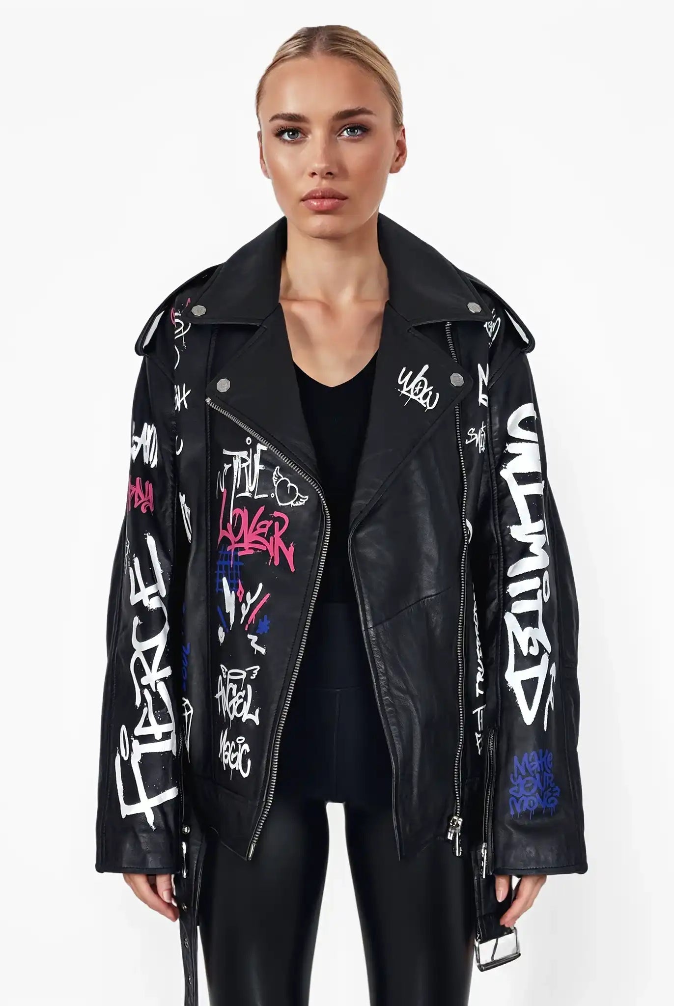 Eine Frau steht mit dem Gesicht nach vorne und trägt die trueprodigy Anya Jacke mit bunten Texten und Motiven, ein schwarzes Oberteil und schwarze Leggings vor einem schlichten weißen Hintergrund.