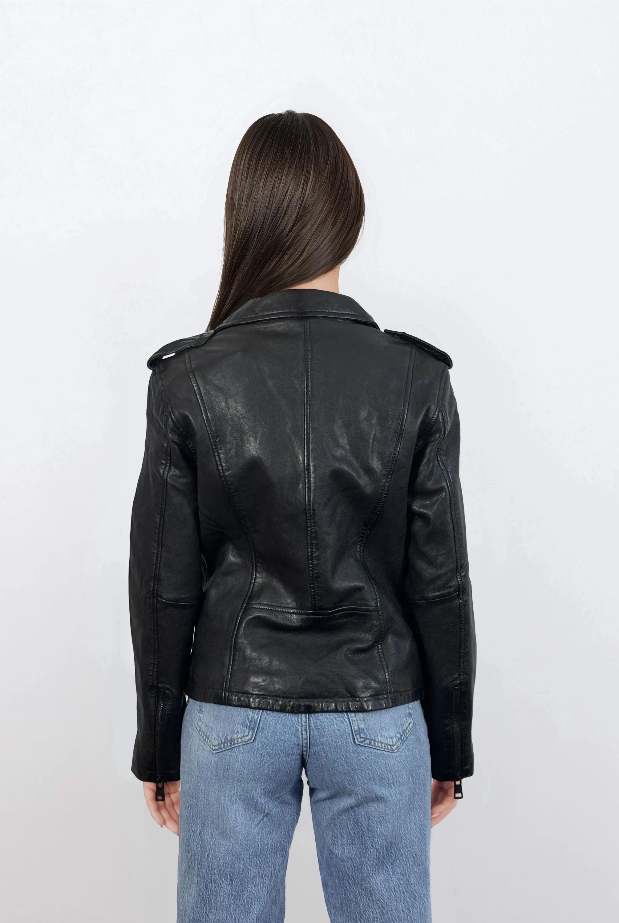 Eine Person mit glattem braunem Haar trägt eine trueprodigy Damen Lederjacke aus Schafsleder in Schwarz im klassischen Biker-Stil und Blue Jeans und steht mit dem Rücken zur Kamera vor einem schlichten weißen Hintergrund.