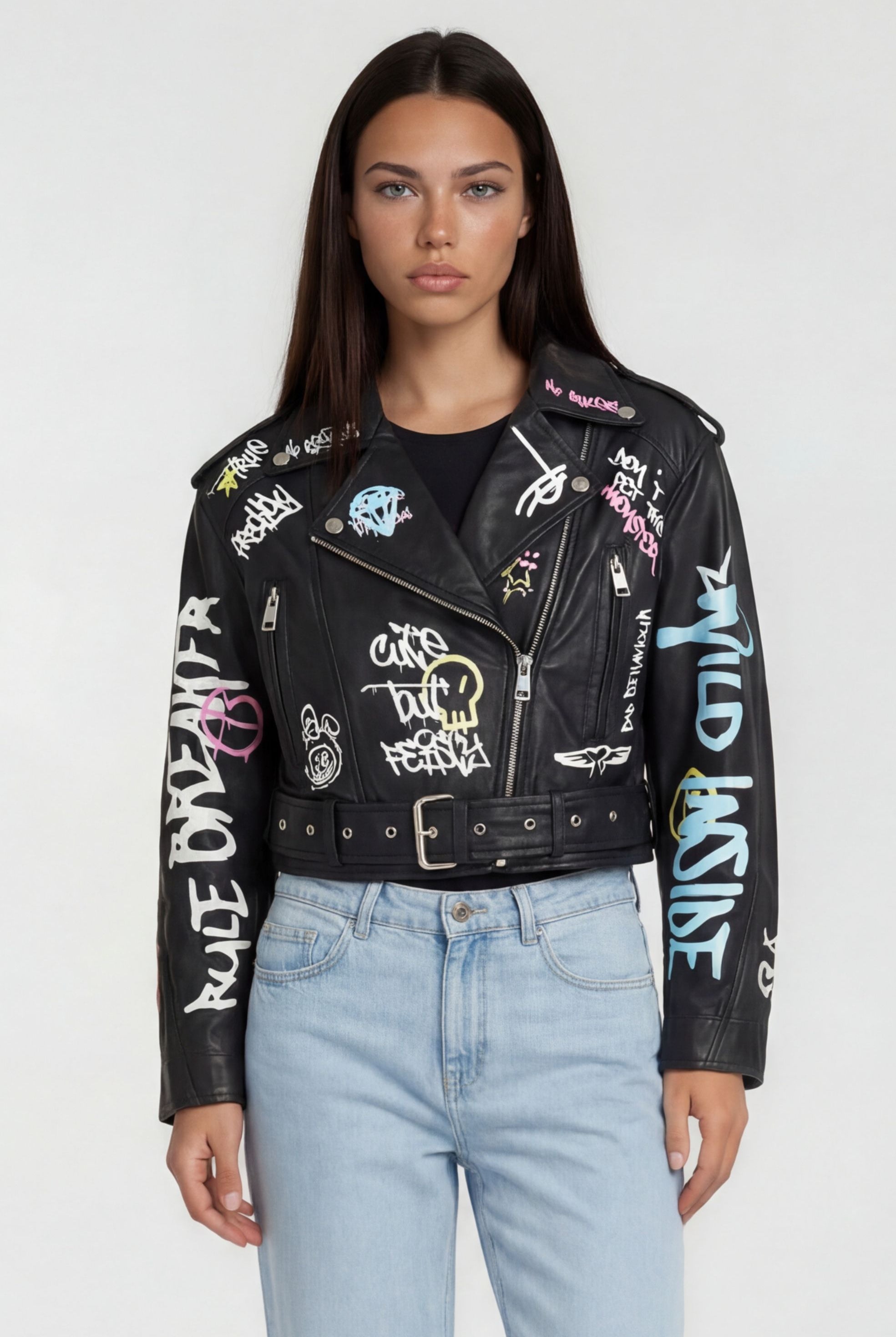 Eine Person mit glattem dunklem Haar trägt die trueprodigy Oversize Lederjacke mit Grafittiprint und Gürtel, gestylt mit hellblauen High-Waisted Jeans, vor einem schlichten hellen Hintergrund.