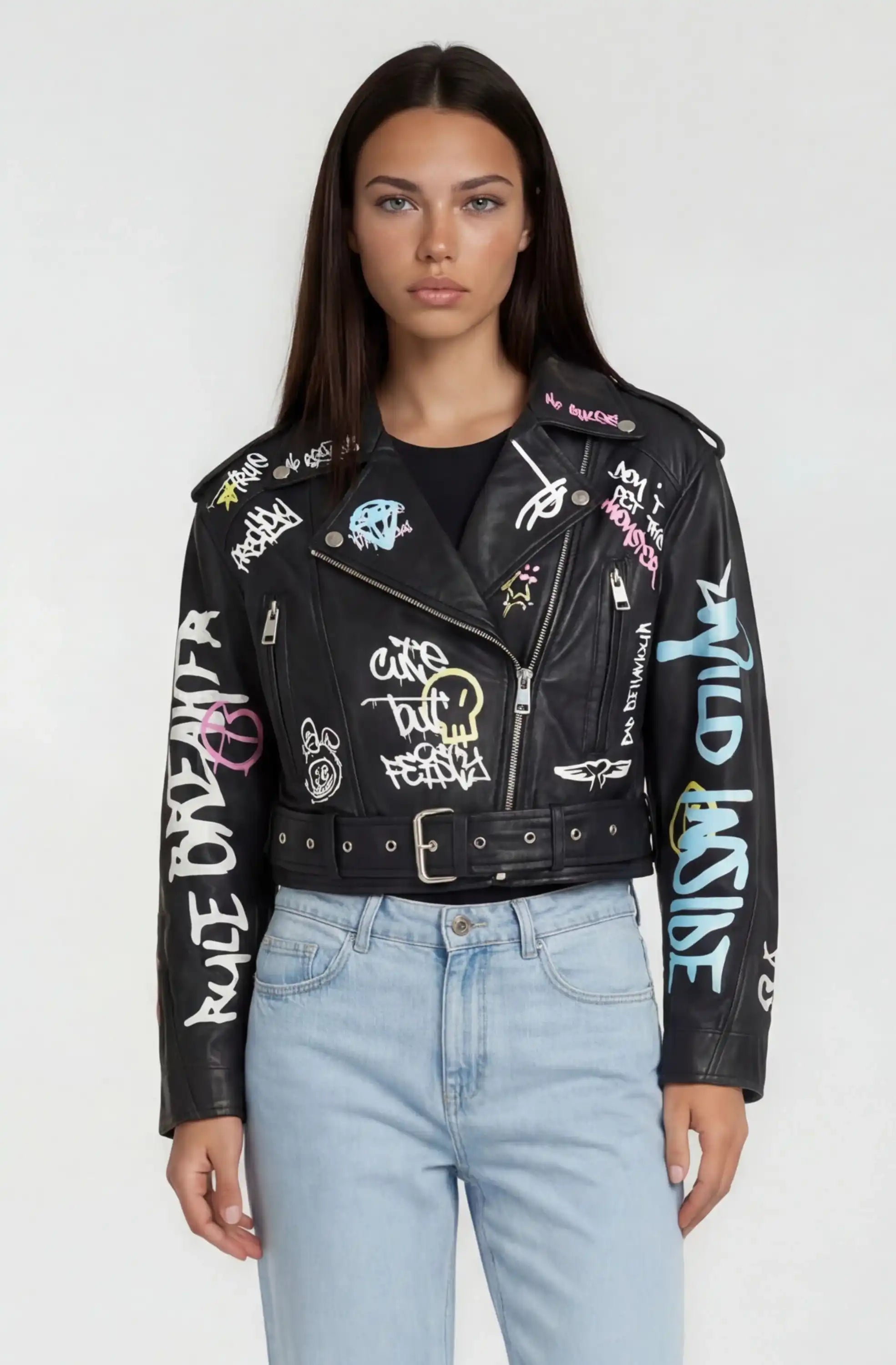 Eine Person mit glattem dunklem Haar trägt die trueprodigy Oversize Lederjacke mit Grafittiprint und Gürtel, gestylt mit hellblauen High-Waisted Jeans, vor einem schlichten hellen Hintergrund.