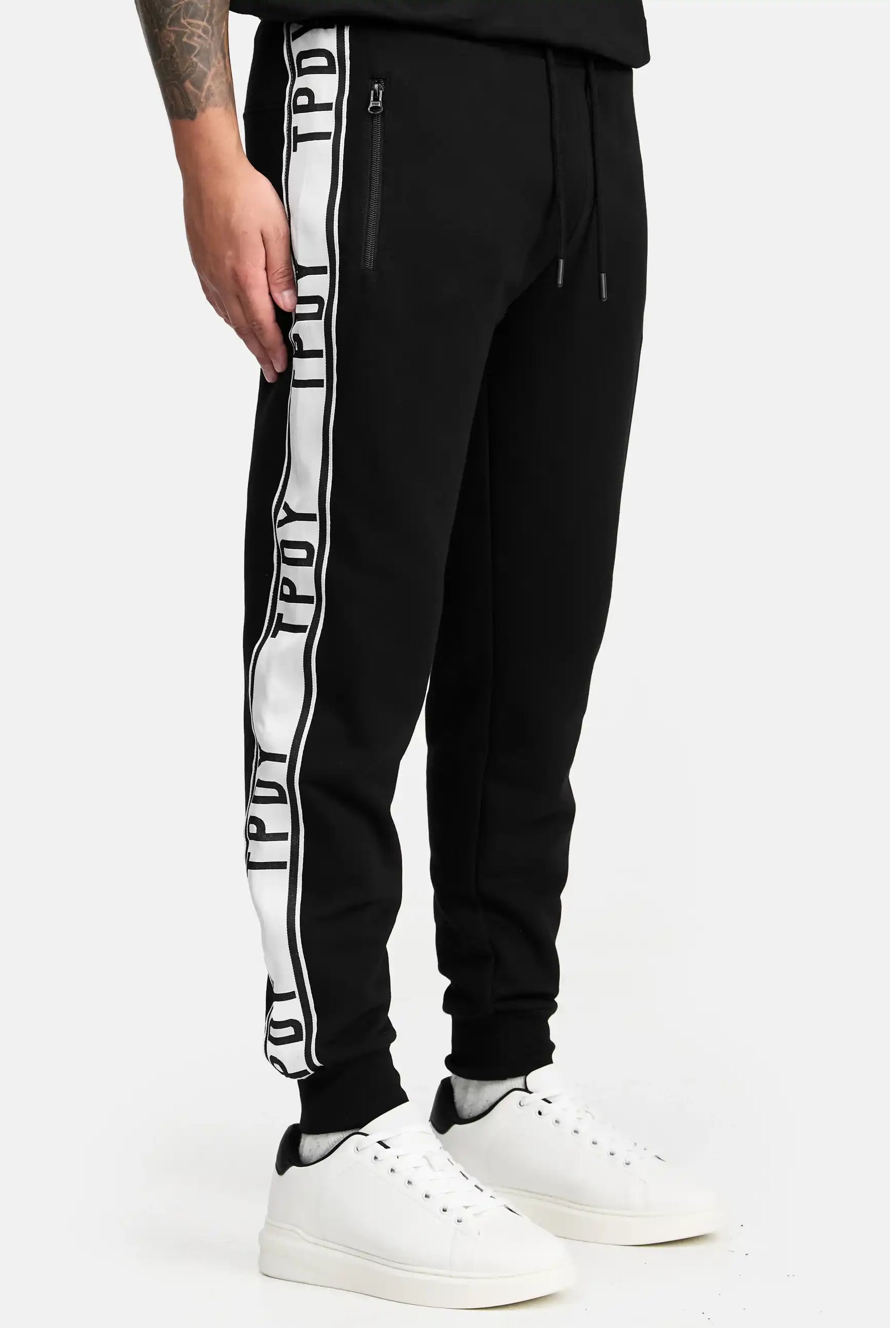 Eine Person trägt die trueprodigy Weston Sweathose mit Logoschrift und weißen Sneakern. Nur die untere Körperhälfte ist vor neutralem Hintergrund zu sehen.