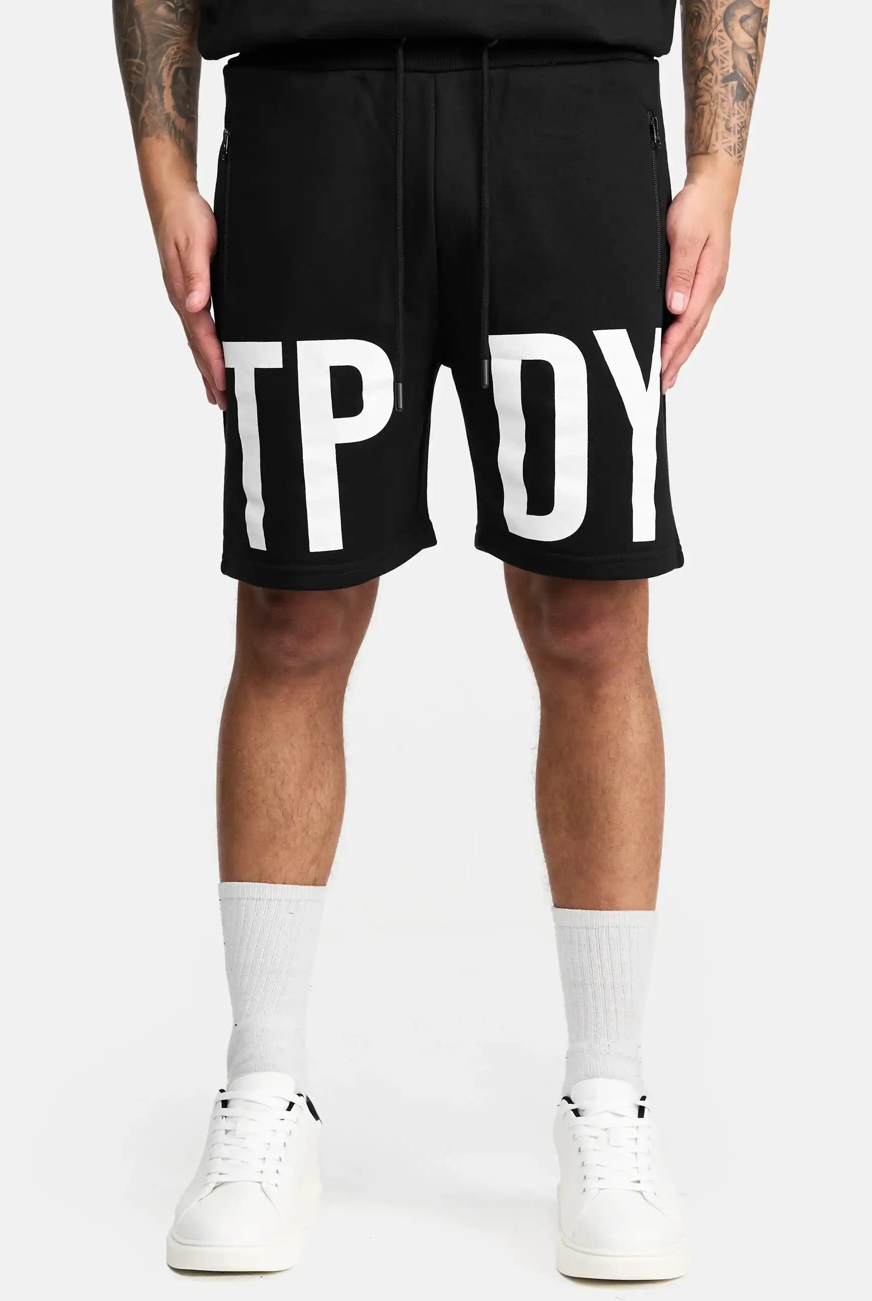 Eine Person trägt die trueprodigy Walden Sweatshort mit Print mit großen weißen Buchstaben TPY und DY, gepaart mit weißen Crew-Socken und Sneakers, vor einem schlichten hellen Hintergrund. Diese Shorts bieten einen modernen Schnitt für einen trendigen Look.