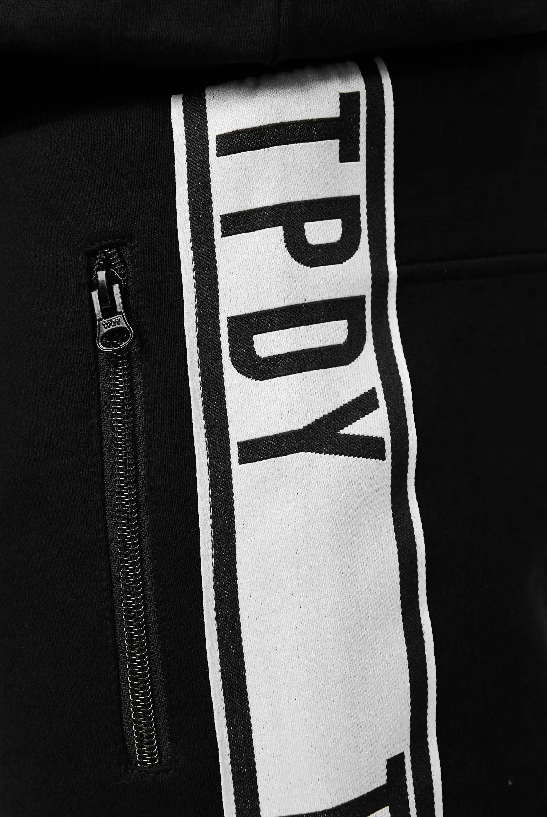 Nahaufnahme der trueprodigy Benjamin Logo Short mit vertikalem weißem Kontraststreifen und fettem TPDY-Schriftzug sowie einer Reißverschlusstasche mit schwarzem Reißverschluss auf der linken Seite.