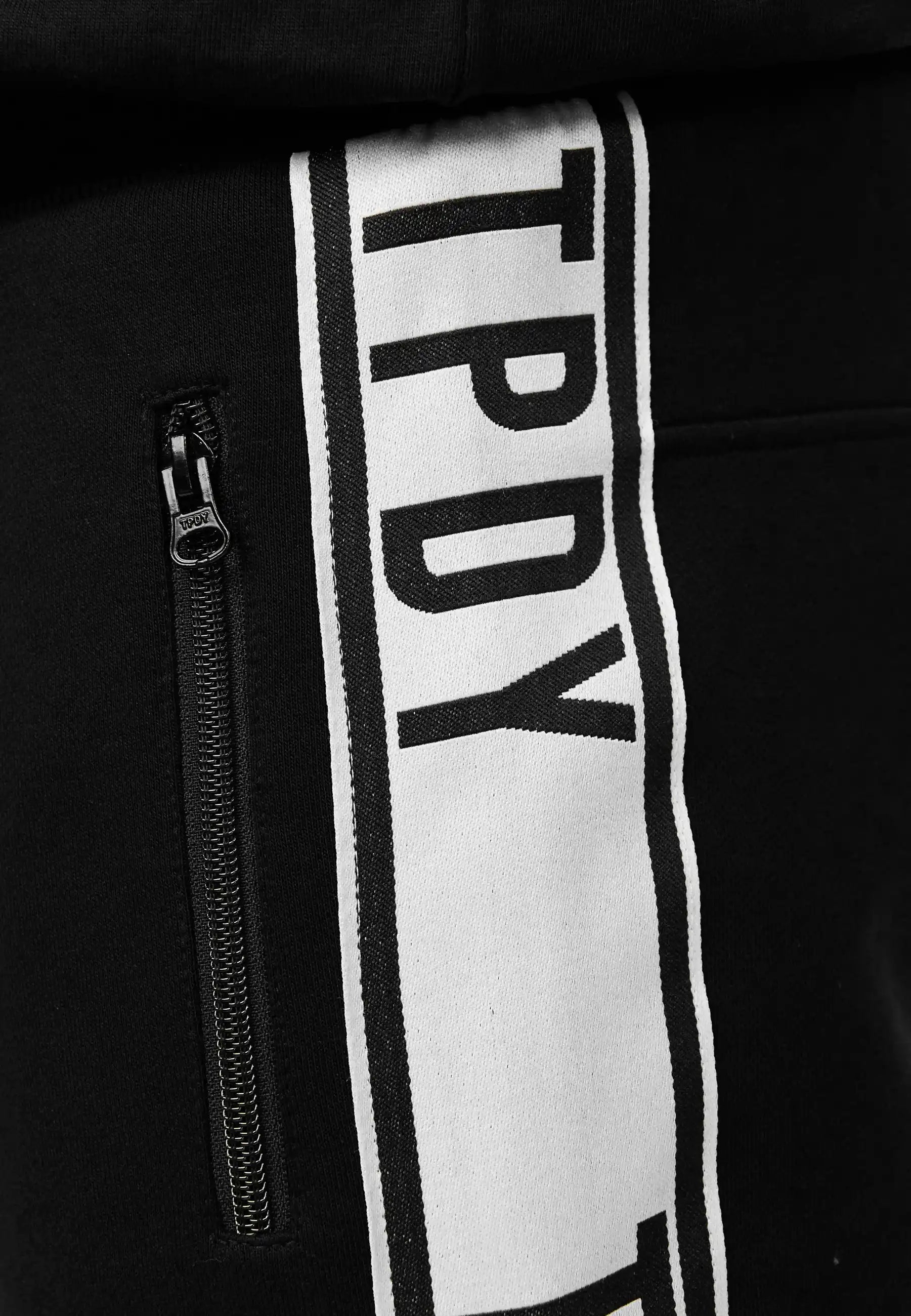Nahaufnahme der trueprodigy Benjamin Logo Short mit vertikalem weißem Kontraststreifen und fettem TPDY-Schriftzug sowie einer Reißverschlusstasche mit schwarzem Reißverschluss auf der linken Seite.