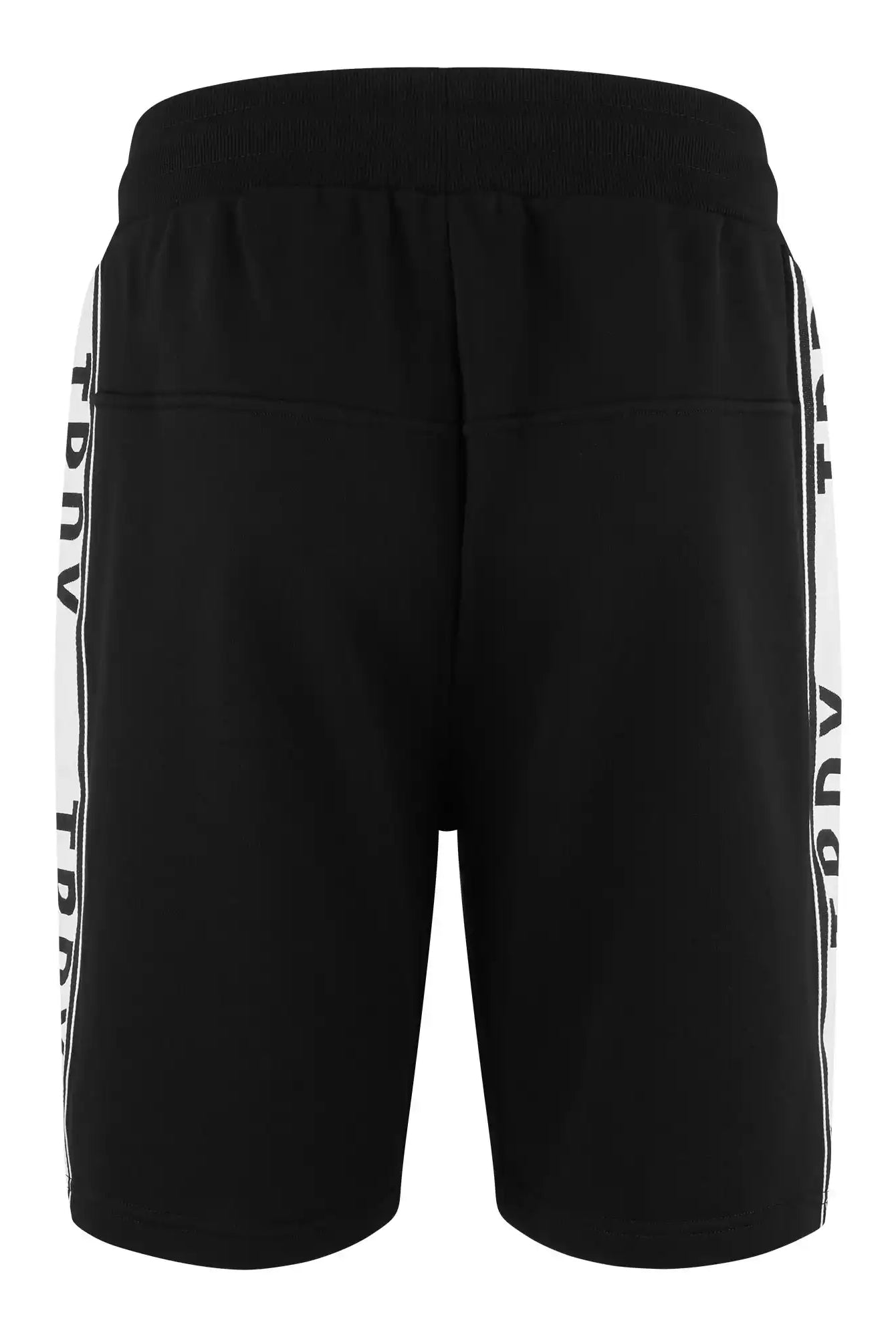 Die Benjamin Logo Short von trueprodigy ist eine schwarze, sportliche Sweatshort für Herren, von hinten gesehen, mit breitem Gummibund und weißen Kontraststreifen mit vertikalem "TRDV"-Print. Ihr Design ist schlicht und lässig.