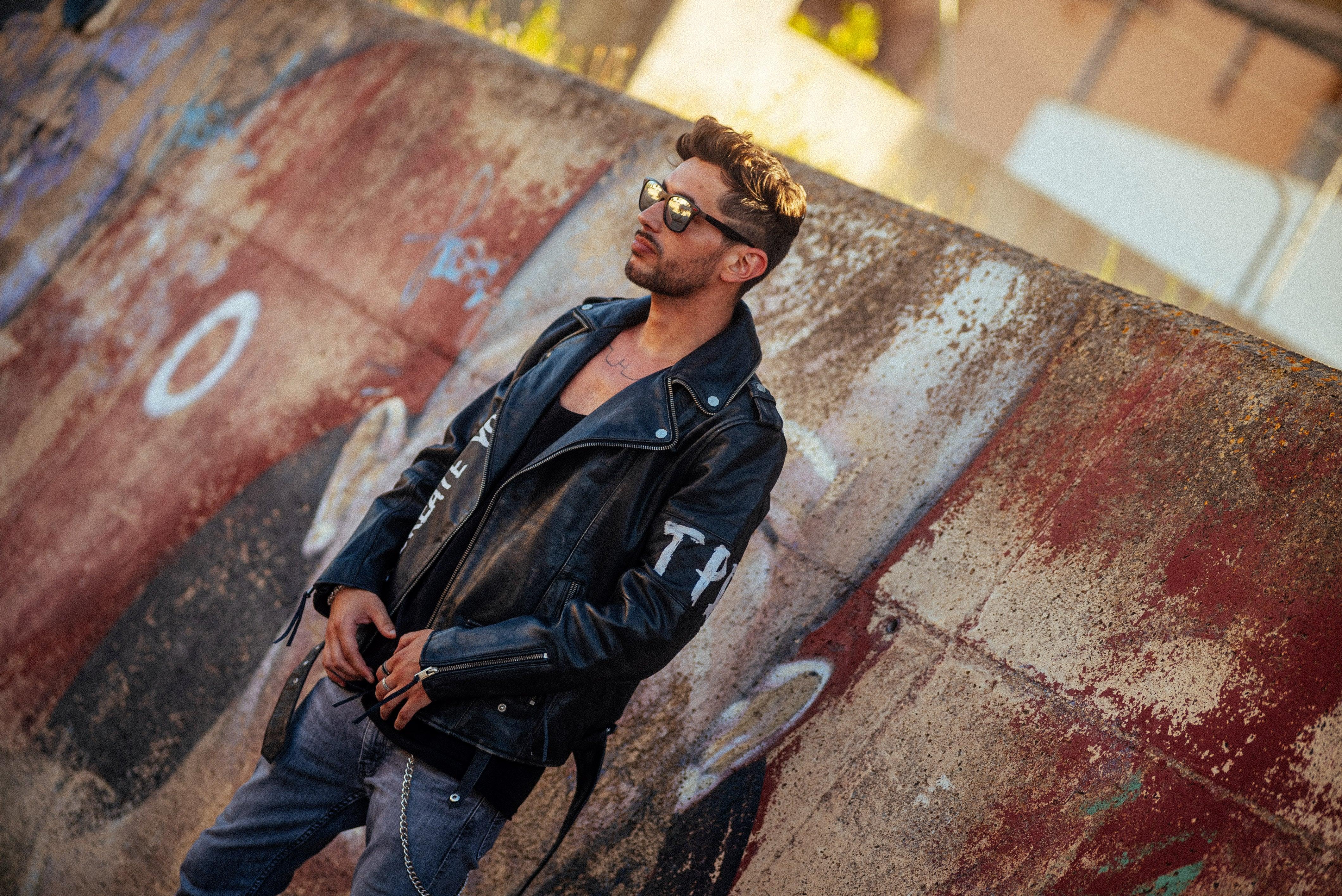 Model Mann mit Lederjacke und T-Shirt vor Mauer an einem Frühlingstag