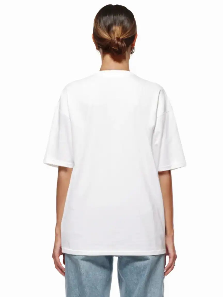 Eine Person steht mit dem Rücken zur Kamera und trägt ein trueprodigy Nika F Damen Oversize-T-Shirt mit TPDY-Stickerei auf der Brust in schlichtem Weiß und hellblaue Jeans vor einem weißen Hintergrund.