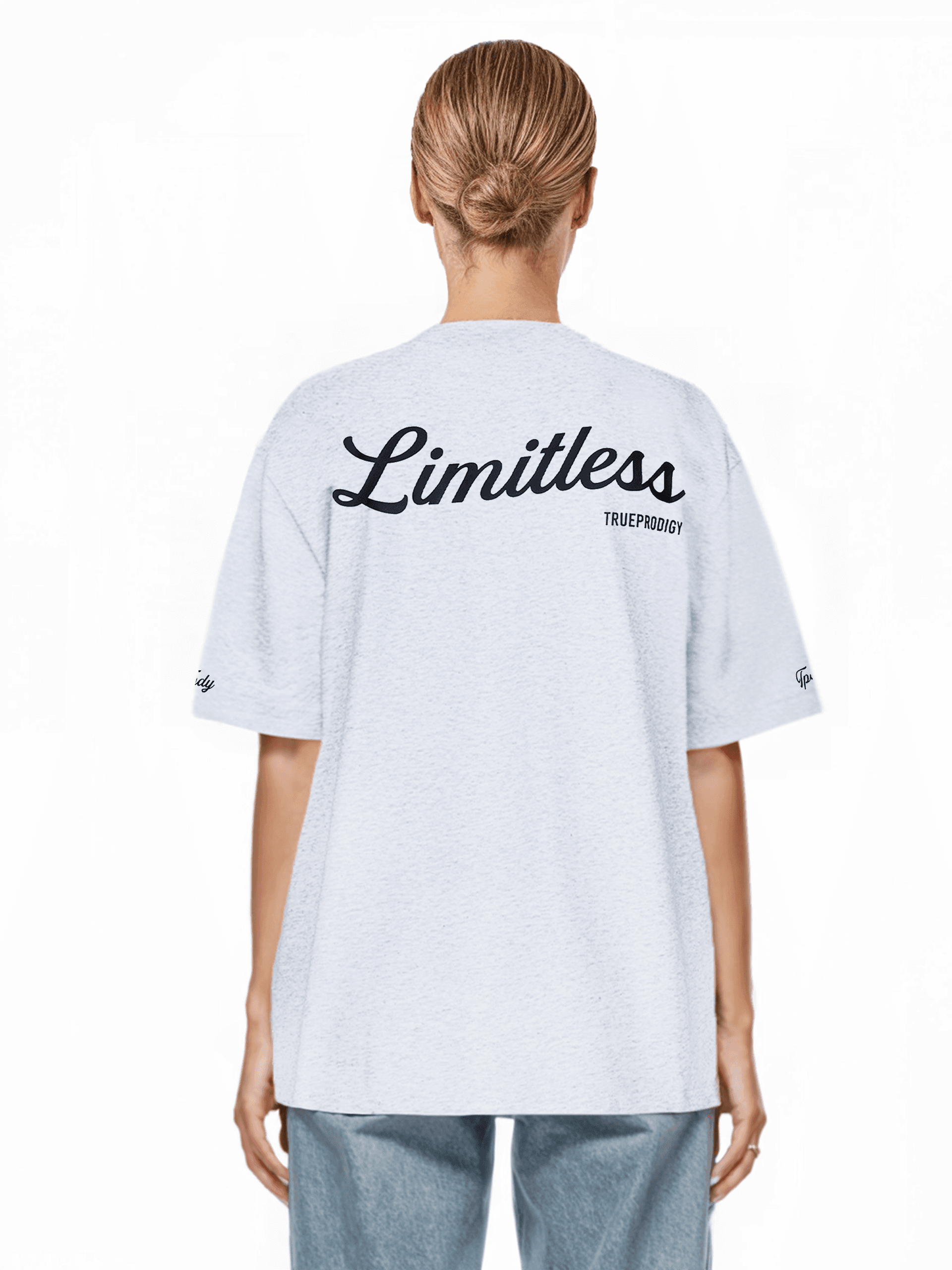 Eine Person mit blonden Haaren zu einem Dutt trägt ein übergroßes weißes „Kai F“ Trueprodigy Unisex-T-Shirt und hellblaue Jeans. Die Rückseite des Shirts aus schwerem Jerseystoff hebt sich vor einem schlichten weißen Hintergrund ab.