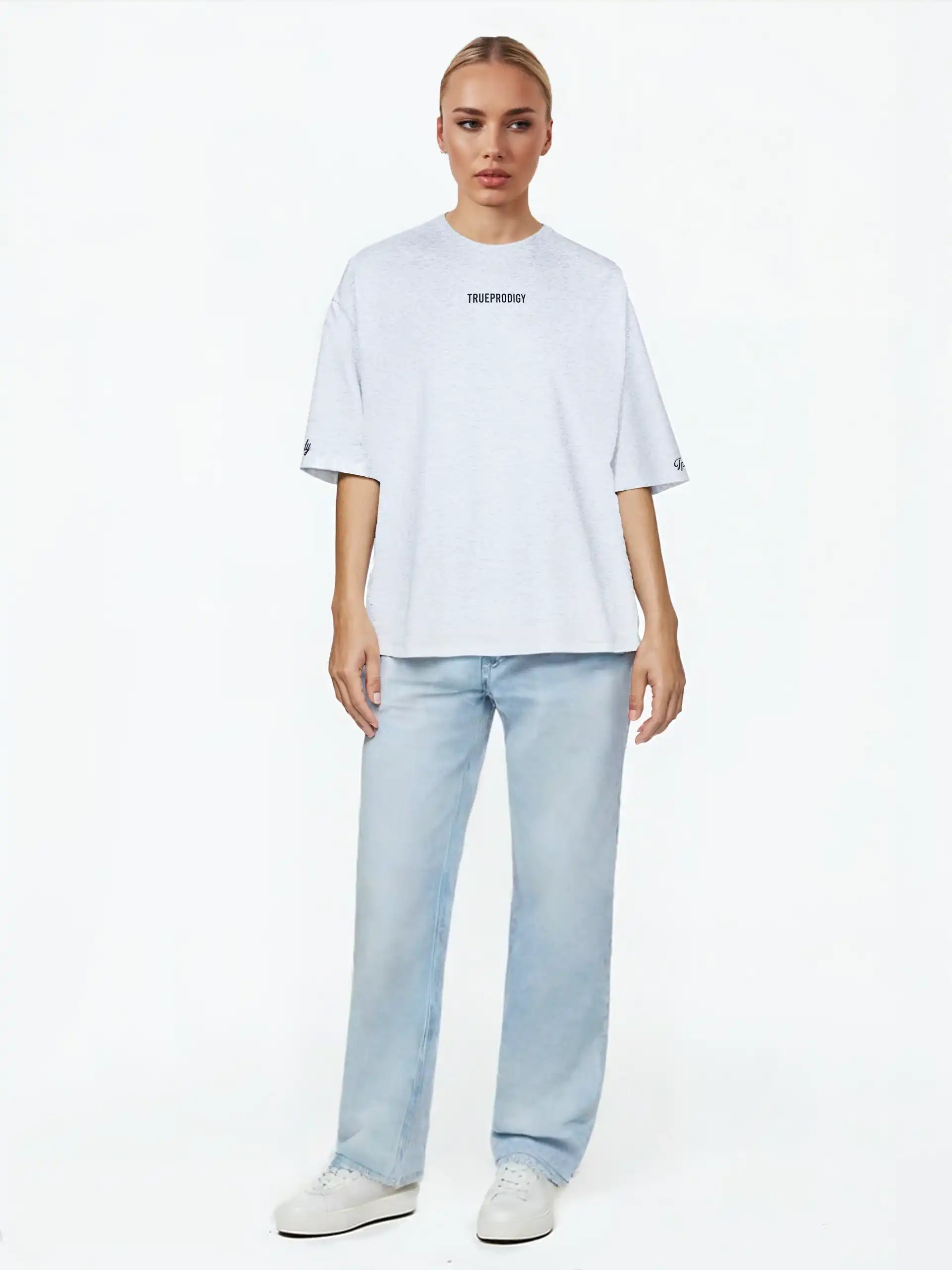 Eine Person blickt nach vorne und trägt das trueprodigy Kai F Oversize-Damen-T-Shirt mit Rückenprint "LIMITLESS", gepaart mit hellblauen Jeans und weißen Turnschuhen, vor einem schlichten weißen Hintergrund.