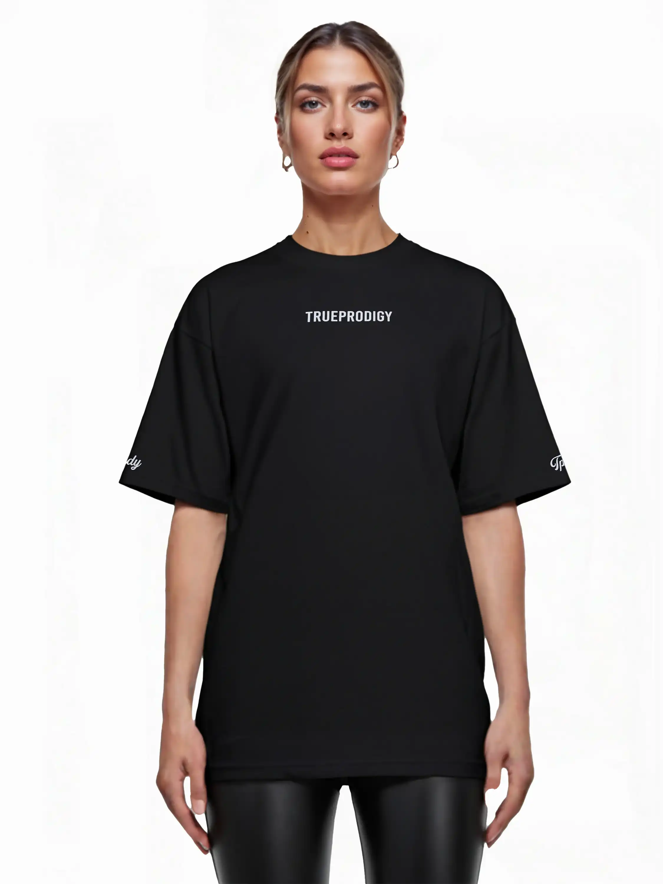 Eine Frau blickt nach vorne und trägt ein schwarzes trueprodigy Kai F Oversize-Damen-T-Shirt mit Rückenprint "LIMITLESS" gepaart mit schwarzen Leggings. Der Hintergrund ist einfarbig weiß.