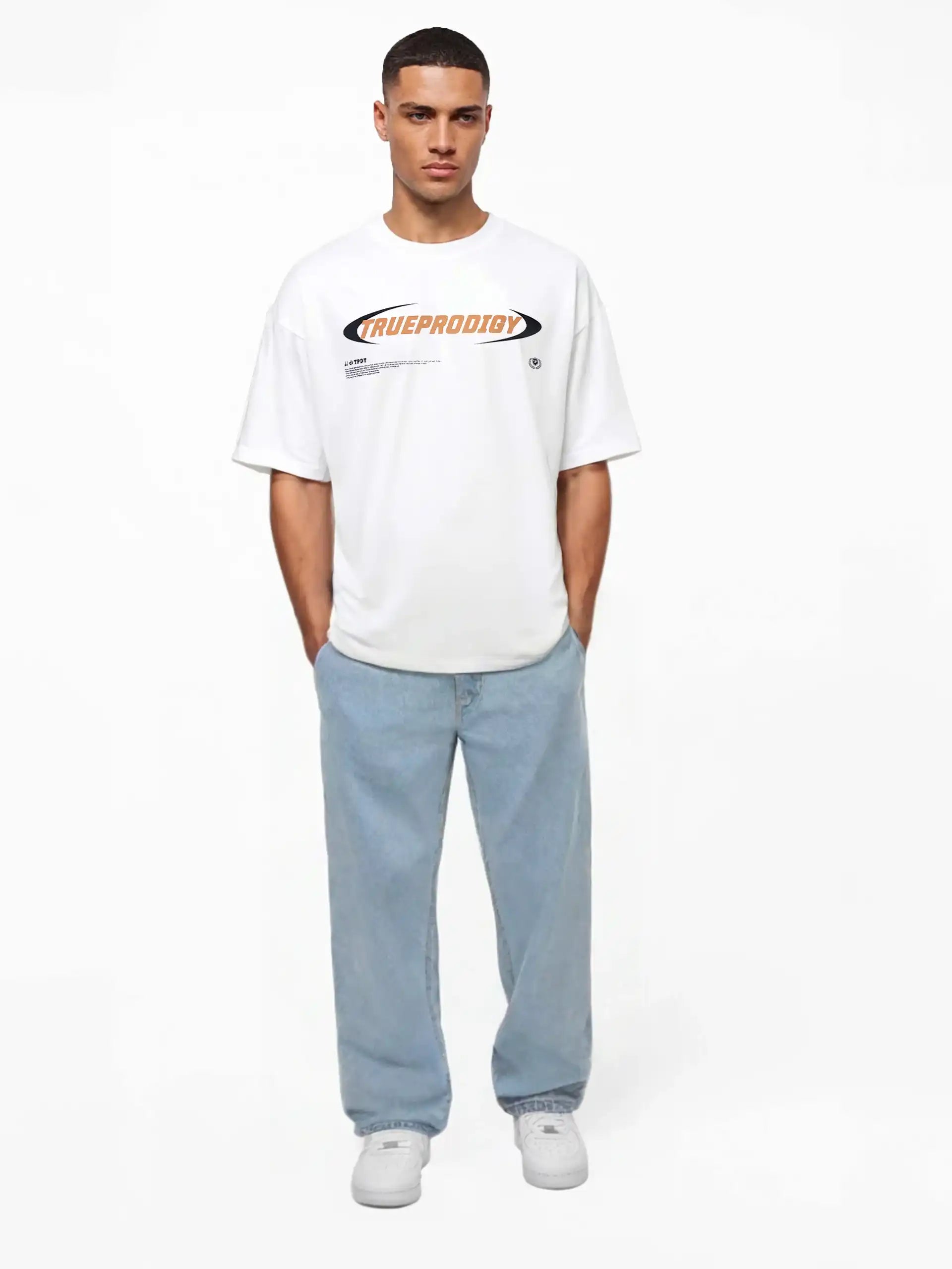Ein Mann steht mit Blick nach vorne und trägt das trueprodigy Ravi Oversize-Shirt mit großem trueprodigy-Schriftzug vorn in weiß, gepaart mit hellblauen, locker sitzenden Jeans und weißen Turnschuhen. Der Hintergrund ist einfarbig weiß.