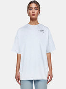 Eine Person trägt das trueprodigy Marin F Oversize-T-Shirt mit feinem Logo-Schriftzug und TPDY-Druck auf dem Ärmel in Hellgrau, gepaart mit hellblauen Jeans, vor einem schlichten weißen Hintergrund.