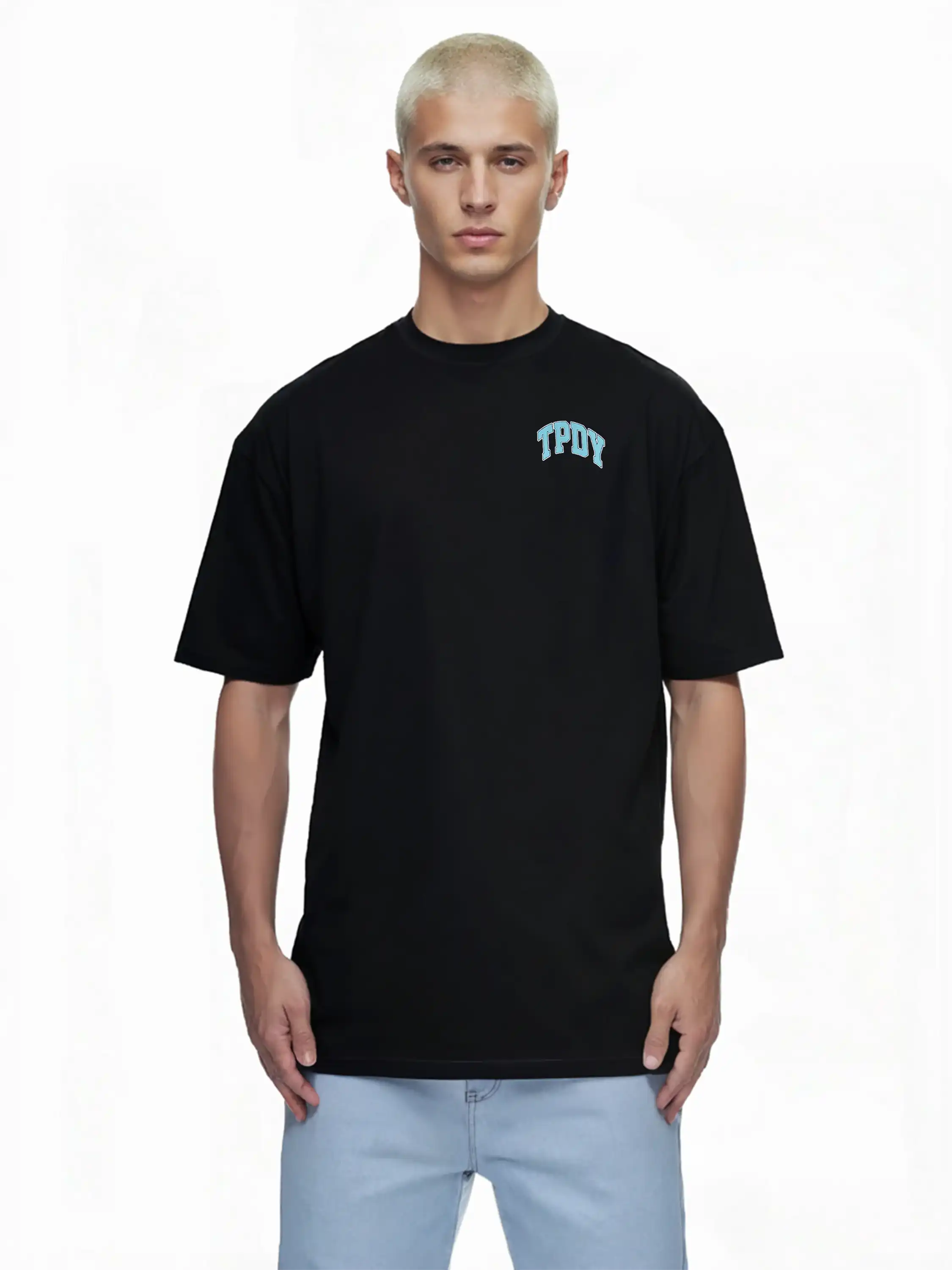 Eine Person mit kurzen, gebleichten blonden Haaren trägt ein trueprodigy Oversize-Shirt mit TPDY-Logo & Rückenprint "Stay Real" und eine hellblaue Jeans und steht vor einem schlichten weißen Hintergrund.