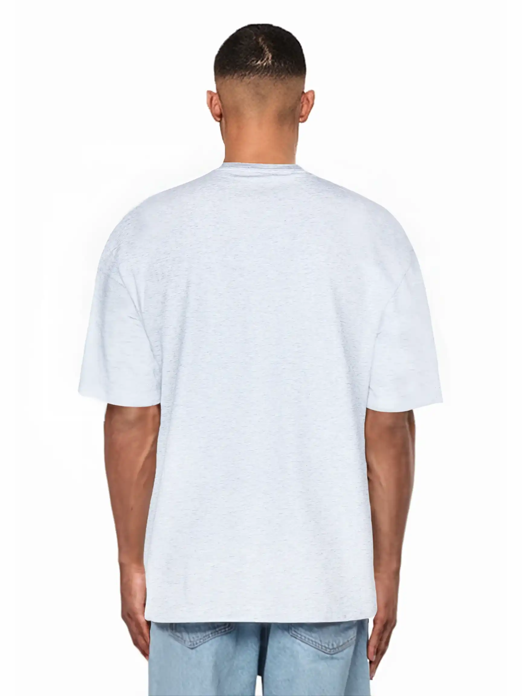 Ein Mann, der mit dem Rücken zur Kamera steht, trägt ein hellgraues trueprodigy Juniper Oversize-Herren-T-Shirt mit Logo-Smile-Grafik auf der Brust und hellblaue Denim-Shorts vor einem schlichten weißen Hintergrund.