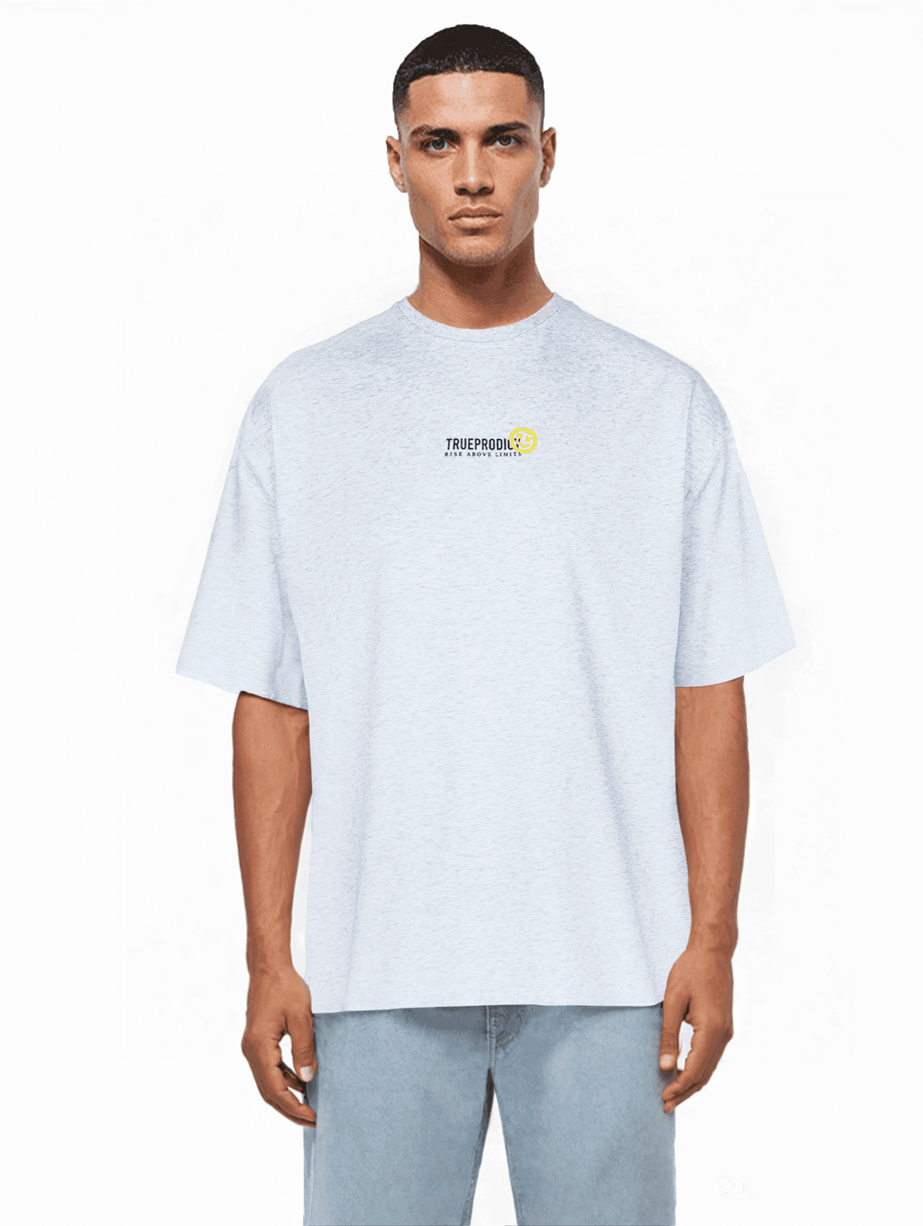 Eine Person mit kurzen Haaren und hellblauen Jeans blickt vor einem weißen Hintergrund nach vorne. Sie trägt „Juniper“ von trueprodigy, ein übergroßes graues T-Shirt aus weichem Jerseystoff mit einem kleinen Logo auf der Brust.