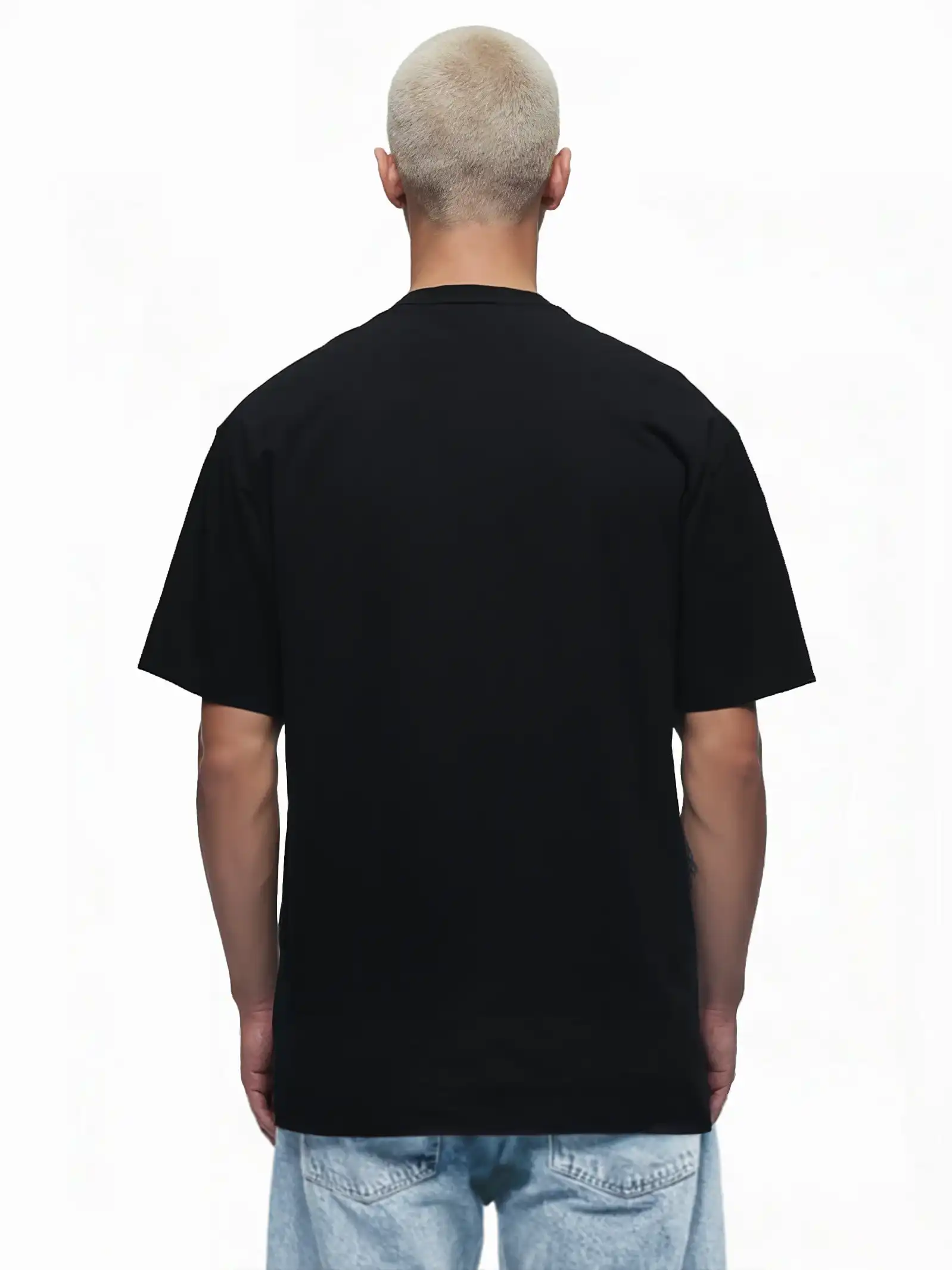 Eine Person mit kurzen, hellen Haaren steht mit dem Rücken zur Kamera, trägt ein schlichtes schwarzes trueprodigy Oversize-Herren-T-Shirt mit Logo-Smile-Grafik auf der Brust und hellblaue Jeans vor einem weißen Hintergrund.