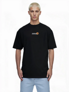 Eine Person mit kurzen blonden Haaren trägt das trueprodigy Oversize-Herren-T-Shirt mit Logo-Smile-Grafik auf der Brust, mit kleinem Logo und orangefarbenem Symbol auf der linken Brust, vor einem schlichten weißen Hintergrund stehend und nach vorne schauend.