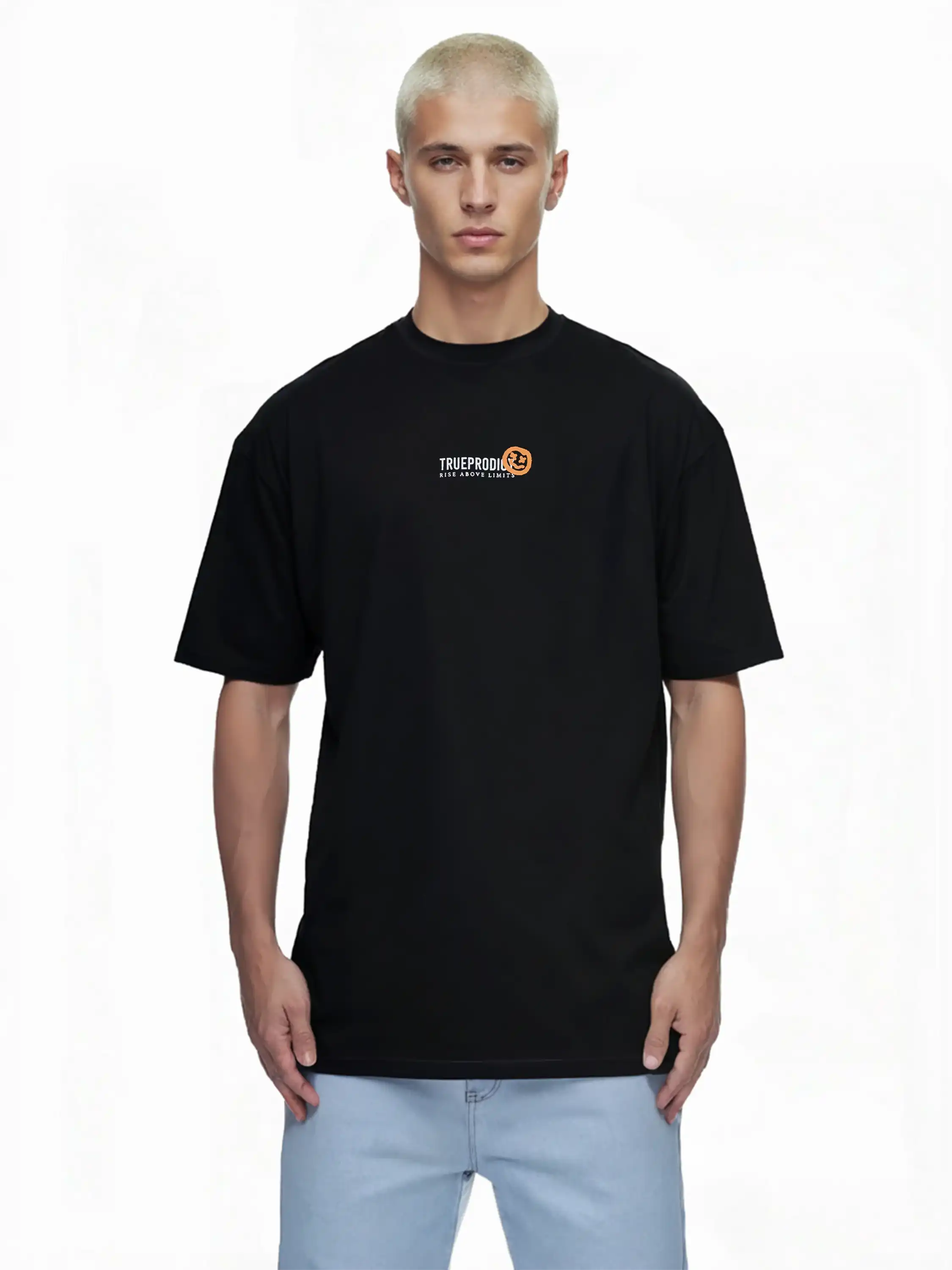 Eine Person mit kurzen blonden Haaren trägt das trueprodigy Oversize-Herren-T-Shirt mit Logo-Smile-Grafik auf der Brust und hellblaue Jeans und steht vor einem schlichten weißen Hintergrund.