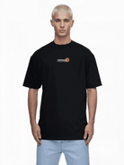 Eine Person mit kurzen blonden Haaren trägt ein schwarzes Unisex-T-Shirt von trueprodigy aus Jerseystoff. Es trägt ein rundes Logo mit der Aufschrift „TRUECOOL THE FUTURE STARTS NOW“. Sie steht in hellblauen Jeans vor einem schlichten weißen Hintergrund. Das T-Shirt heißt Juniper.