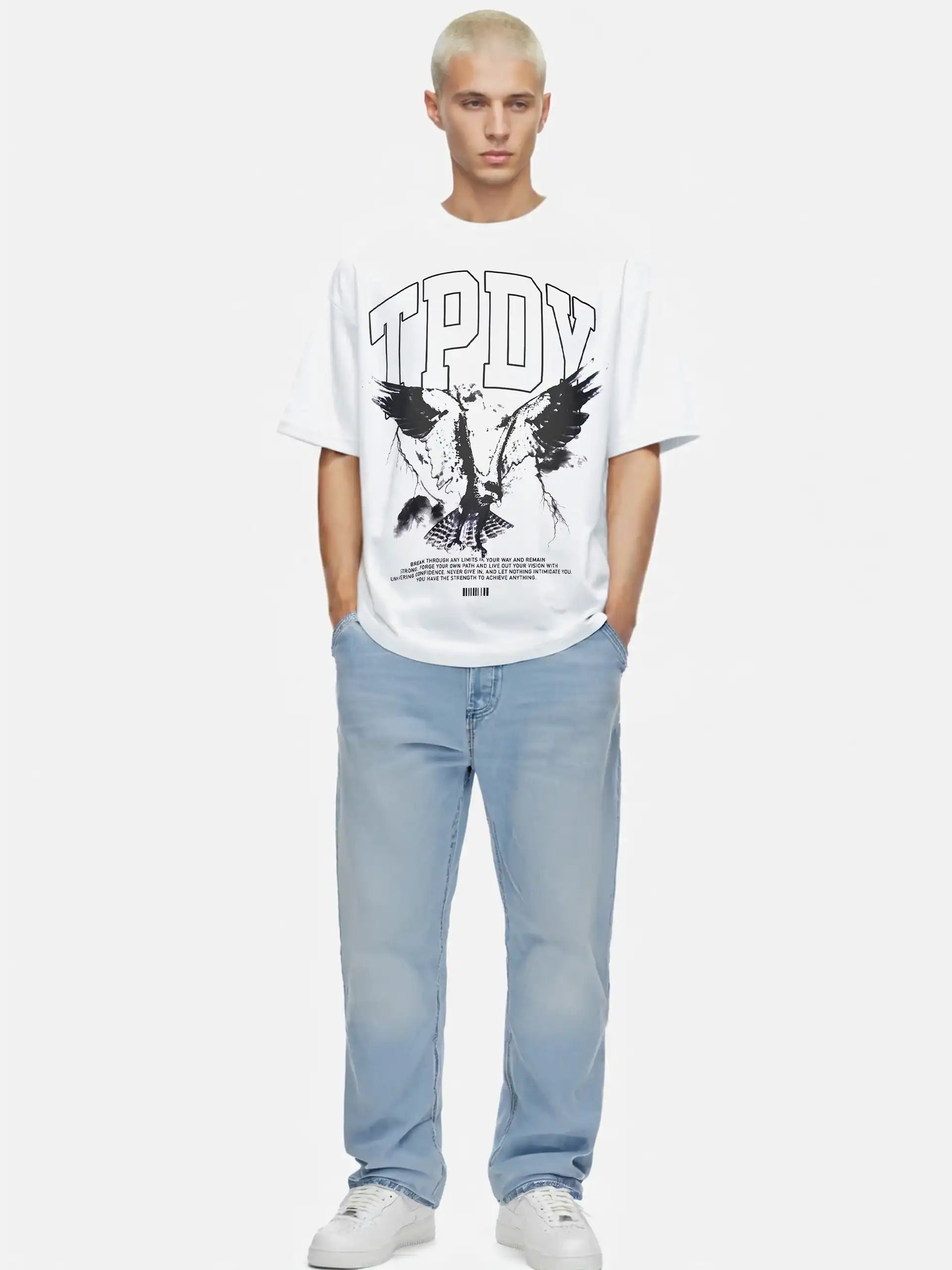 Eine Person mit kurzen gebleichten Haaren trägt das trueprodigy Yuki Oversize-T-Shirt mit Adlergrafik & TPDY-Schriftzug aus schwerem Jerseystoff, gepaart mit hellblauen Jeans und weißen Turnschuhen, vor einem schlichten weißen Hintergrund.