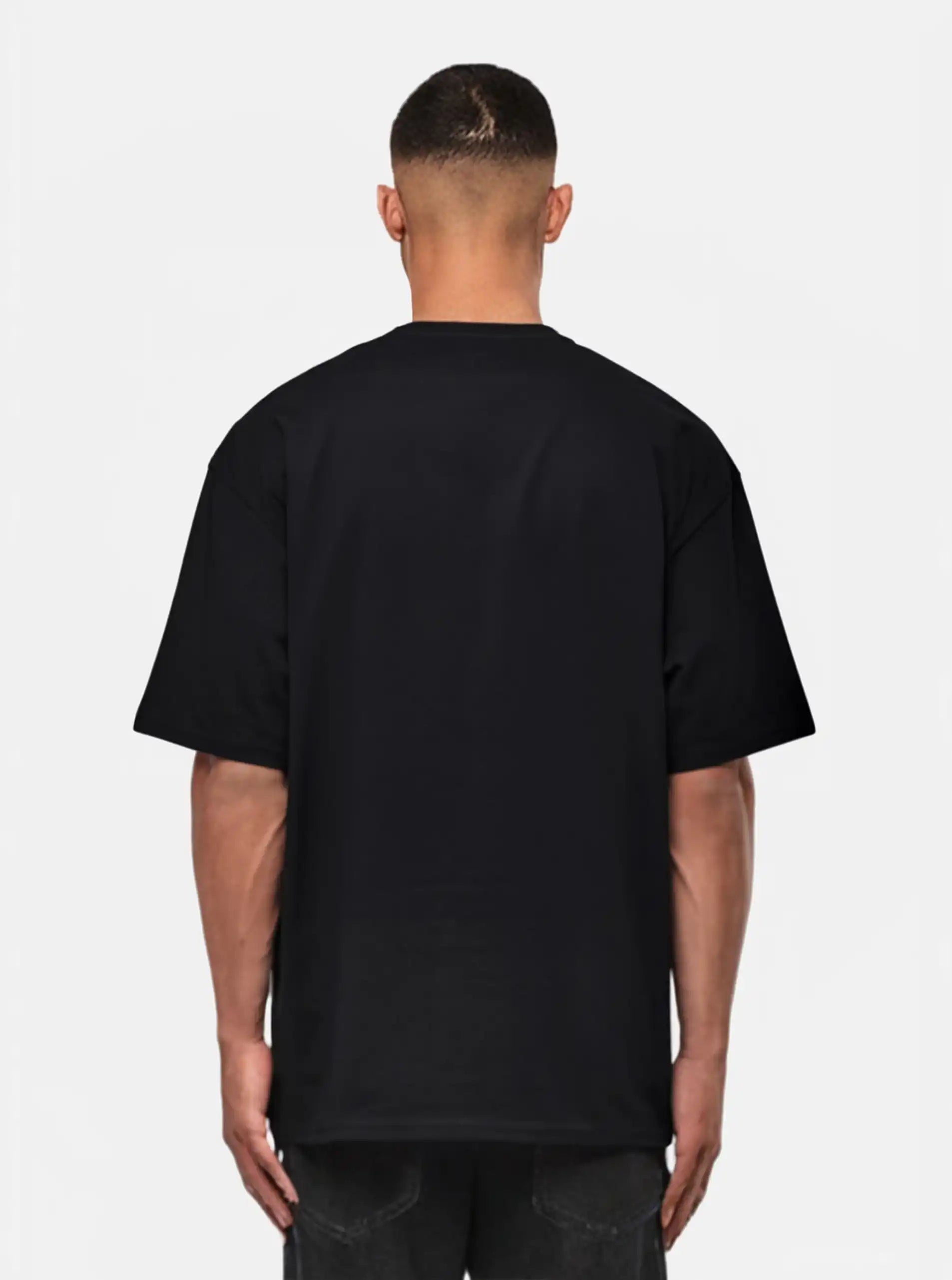 Eine von der Kamera abgewandte Person, die ein trueprodigy Yuki Oversize-T-Shirt mit Adlergrafik & TPDY-Schriftzug und eine dunkle Jeans trägt, steht vor einem weißen Hintergrund.