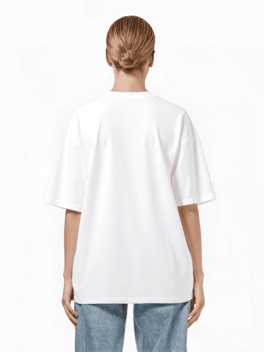 Eine Person mit blondem Dutt blickt abgewandt und trägt ein übergroßes Trueprodigy Yuki F T-Shirt und hellblaue Jeans. Das schlichte weiße Unisex-T-Shirt ergänzt den minimalistischen Hintergrund.