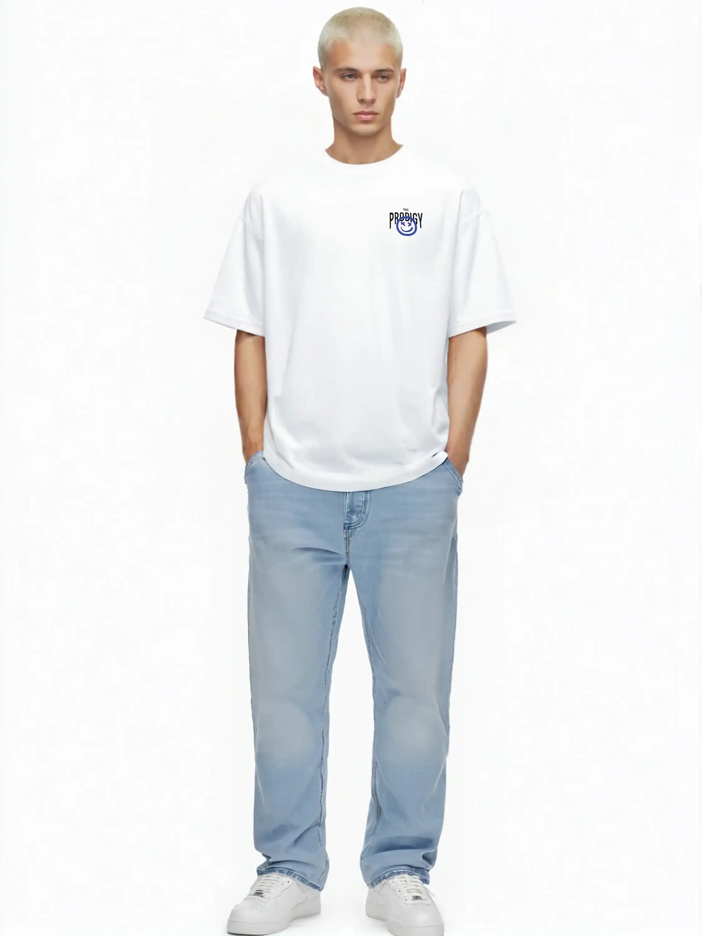 Eine Person mit kurzen blonden Haaren steht vor einem weißen Hintergrund und trägt das trueprodigy Hajin Oversize-T-Shirt mit Spray-Smiley & Rückenprint "Happy Mind", hellblaue Jeans und weiße Sneakers, die Hände lässig in den Taschen.
