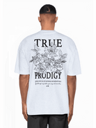 Von hinten ist ein Mann zu sehen, der ein übergroßes, weißes Unisex-T-Shirt „Trueprodigy Alex“ aus Jerseystoff trägt. Auf der Rückseite ist ein Blumenmuster mit der Aufschrift „TRUE PRODIGY“ deutlich zu sehen, darunter dezent ein motivierendes Zitat.