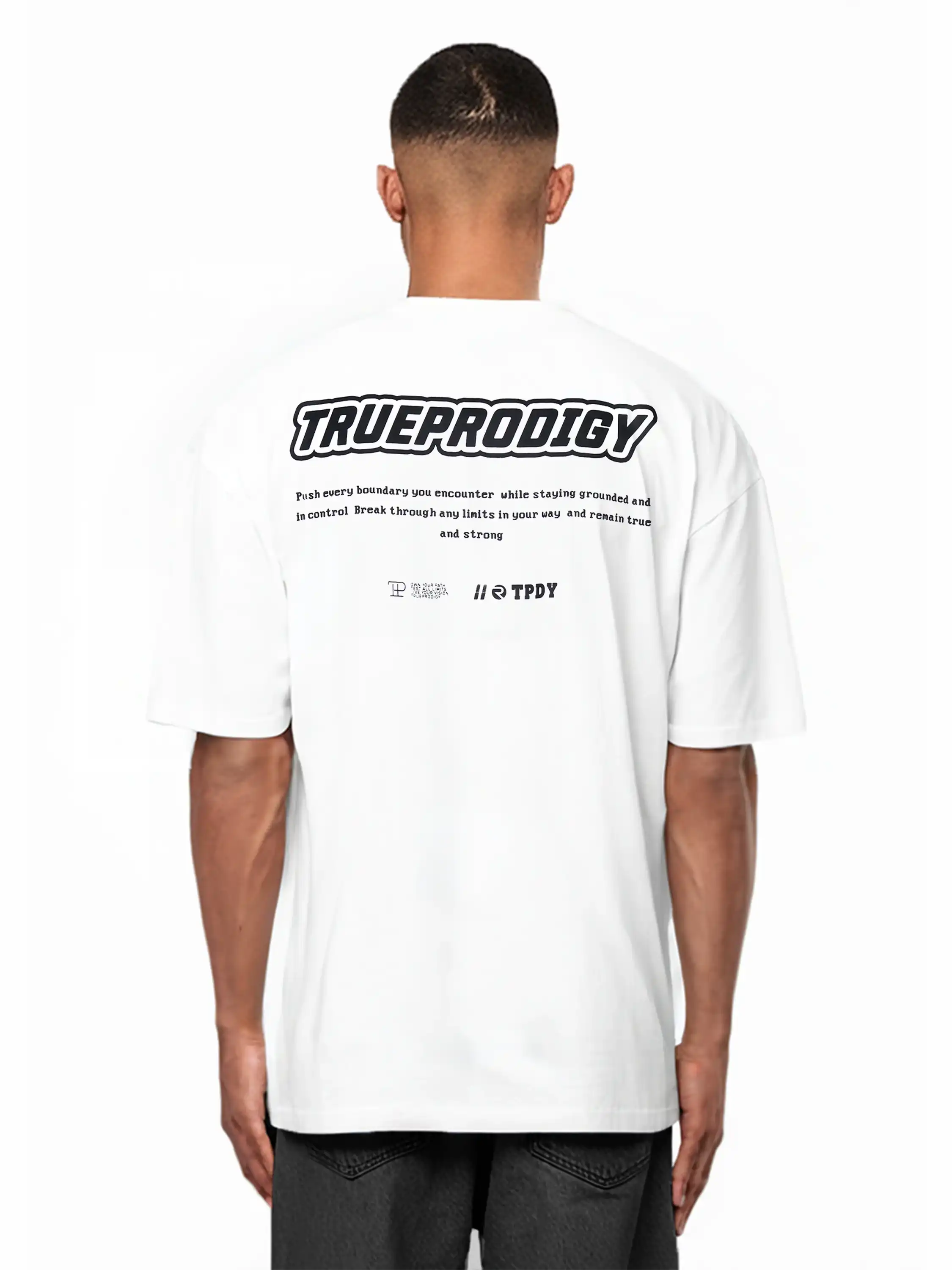Eine Person mit kurzen Haaren trägt dunkle Shorts und das Eden Oversize-Shirt von trueprodigy aus schwerem Jersey, mit einem großen 3D-Logo-Schaumstoffdruck und kleinerem Text auf dem Rücken.