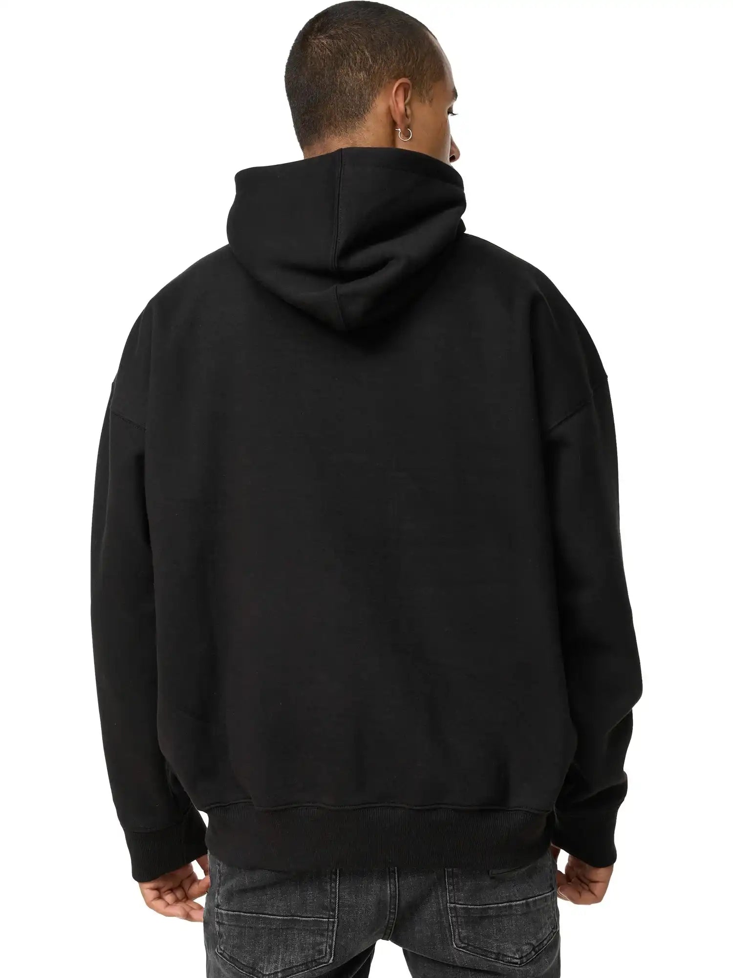 Eine Person mit kurzen Haaren ist von hinten zu sehen. Sie trägt einen trueprodigy Janne Oversized Hoodie mit Print und dunkle Jeans vor einem schlichten weißen Hintergrund.