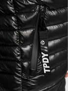 Nahaufnahme einer schwarzen, glänzenden, gesteppten Adan Steppjacke mit Kapuze von trueprodigy. Mit einer vertikalen Reißverschlusstasche und einem schwarzen Anhänger mit weißer Aufschrift "TPDY//".