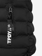 Nahaufnahme einer schwarzen, wasserabweisenden Neo Kurze Pufferjacke mit Logo von trueprodigy, mit einem teilweise geöffneten Reißverschluss mit schwarzem Zug, der den weißen "TPDY//"-Schriftzug und ein rundes Logo zeigt.