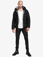 Eine Person steht vor einem schlichten weißen Hintergrund und trägt die trueprodigy Neo Kurze Pufferjacke mit Logo, ein weißes T-Shirt, schwarze Skinny Jeans und schwarze Schnürstiefel.