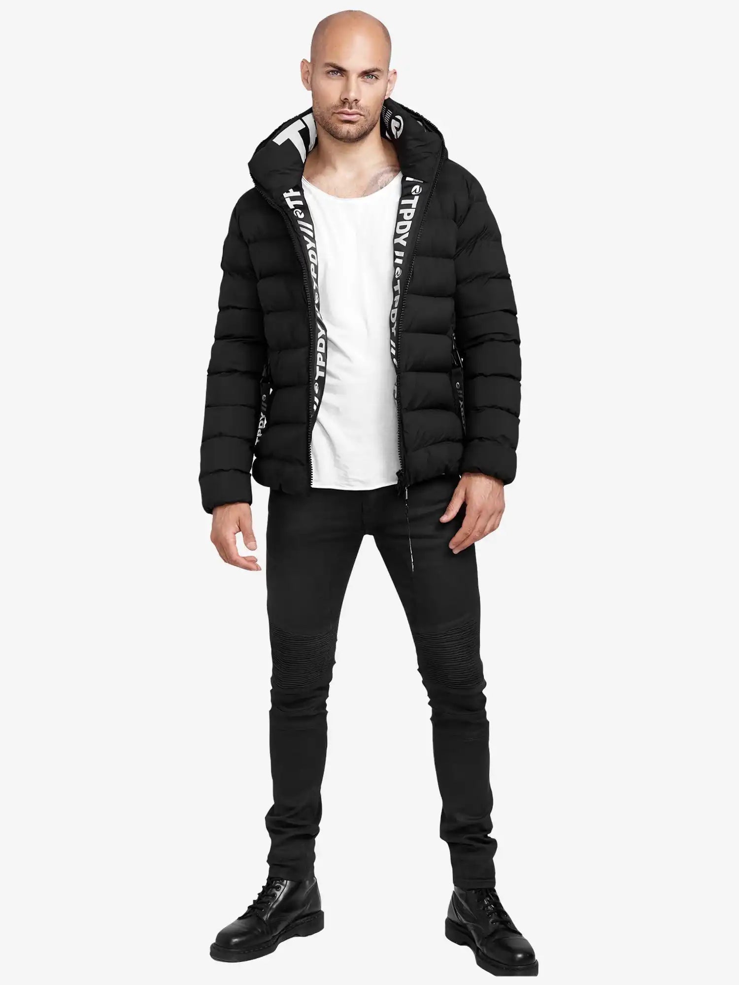 Eine Person steht vor einem schlichten weißen Hintergrund und trägt die trueprodigy Neo Kurze Pufferjacke mit Logo, ein weißes T-Shirt, schwarze Skinny Jeans und schwarze Schnürstiefel.
