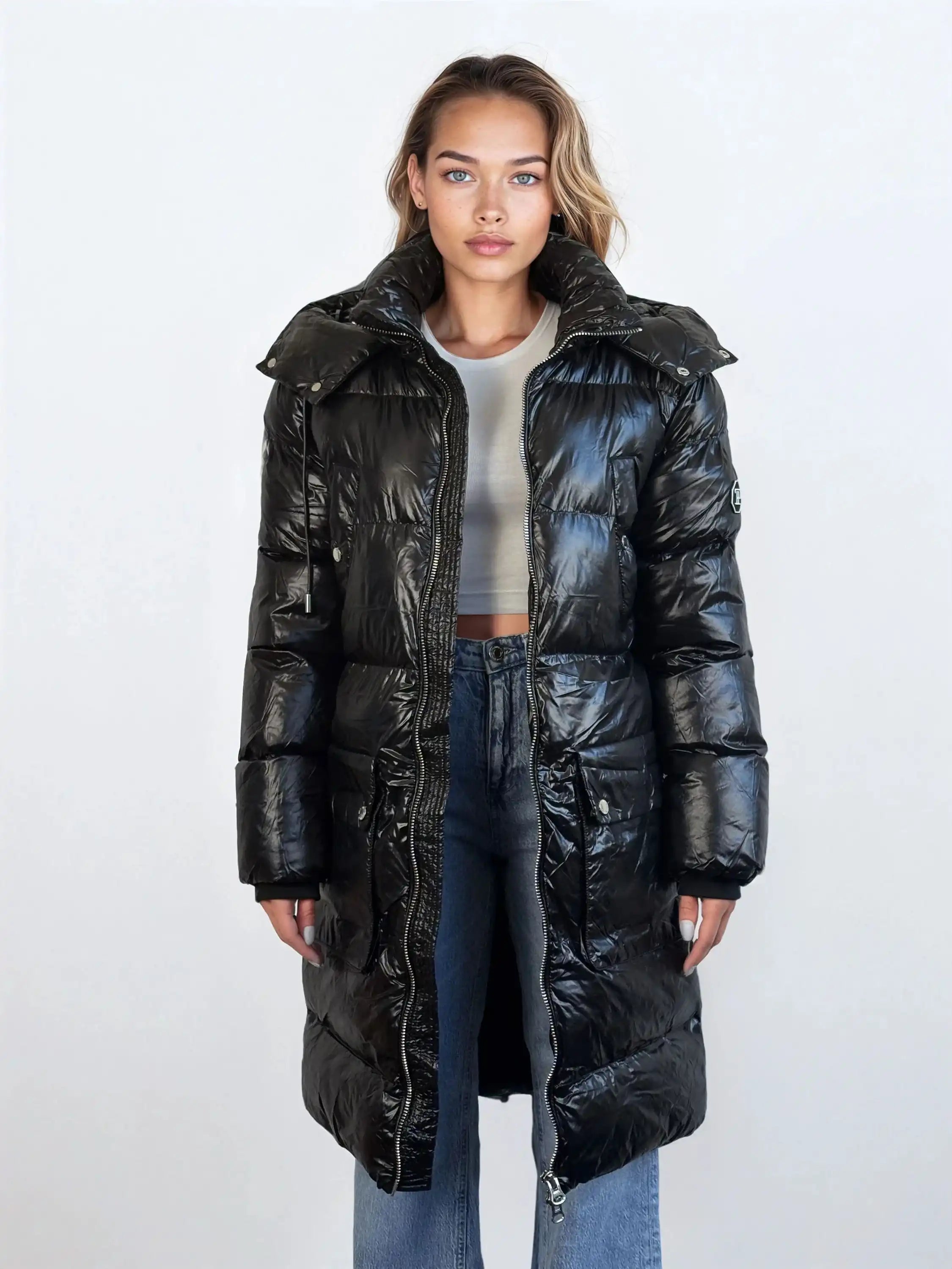 Eine nach vorne blickende Person trägt die trueprodigy Damen Winterjacke mit abnehmbarer Kapuze im Regular Fit über einem hellgrauen Crop Top und blauen Jeans vor einem schlichten hellen Hintergrund.