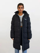 Eine Person trägt einen wasserabweisenden Damen Parka mit fester Kapuze im Regular Fit von trueprodigy über einem hellgrauen kurzen Top und blauen Jeans. Der Parka hat Patches an Brust und Ärmel.